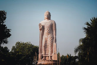 A tall stone statue of buddha stands outdoors.