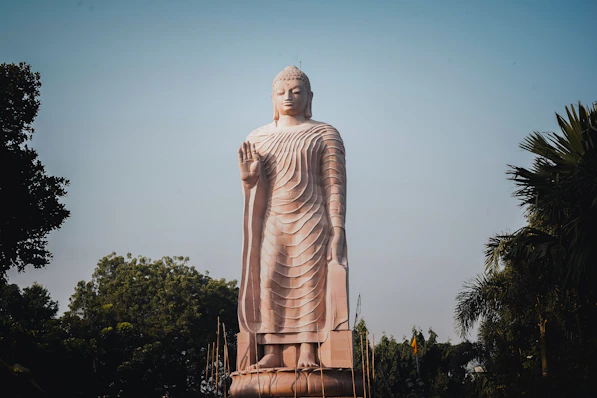 A tall stone statue of buddha stands outdoors.