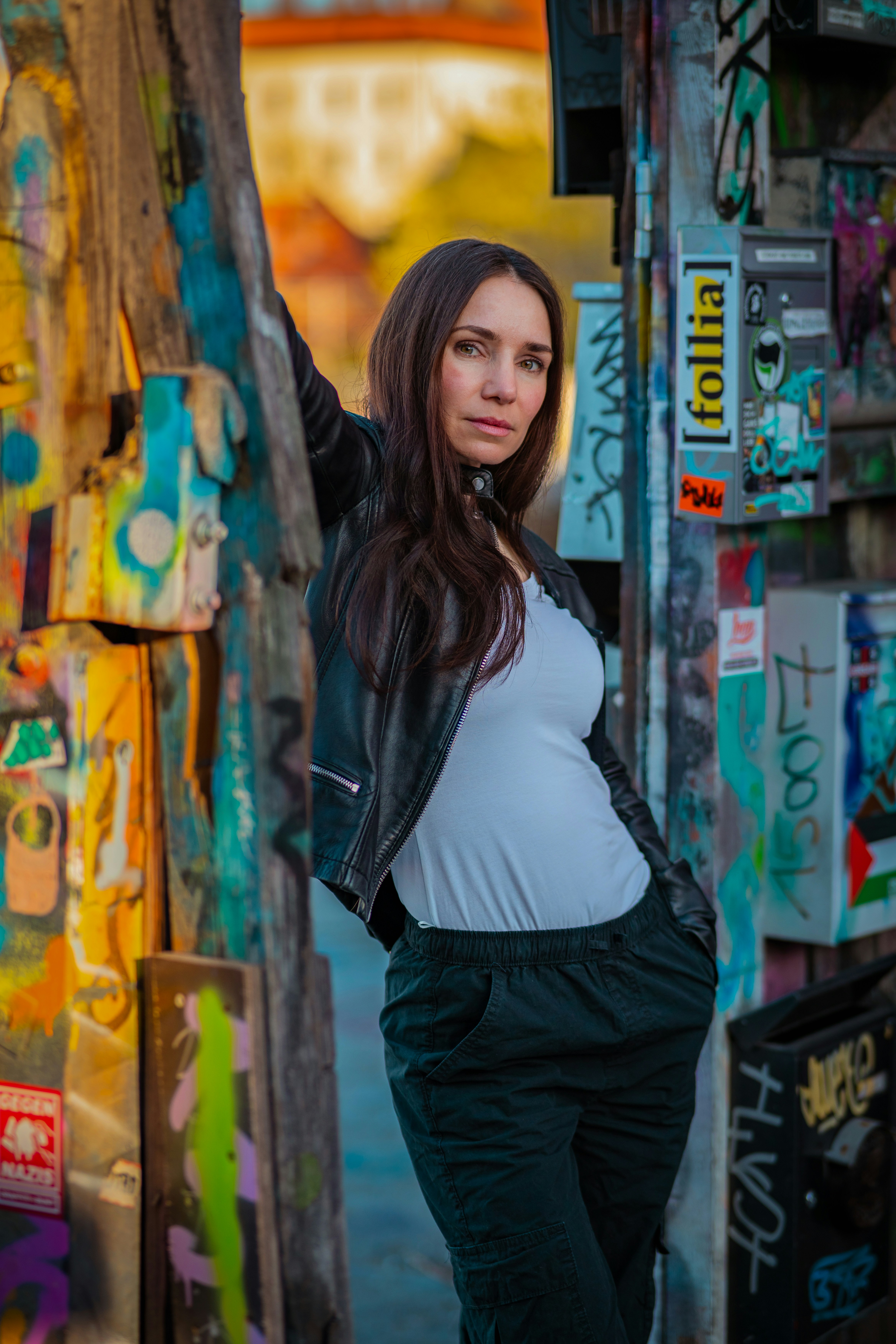 Woman leans against graffiti-covered wall