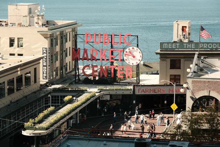 Pike place market center sign with clock and people