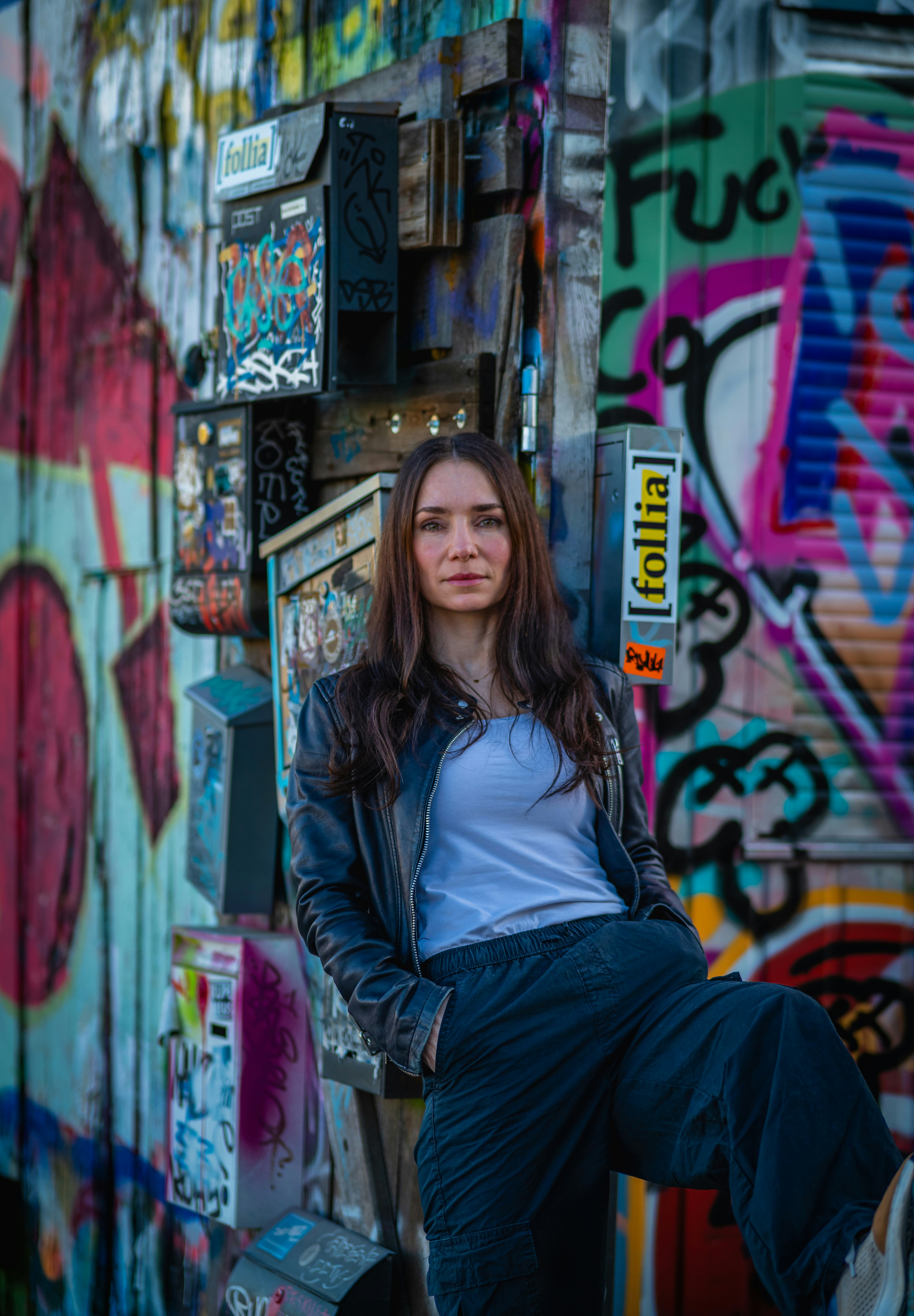 Woman posing against a graffiti-covered wall
