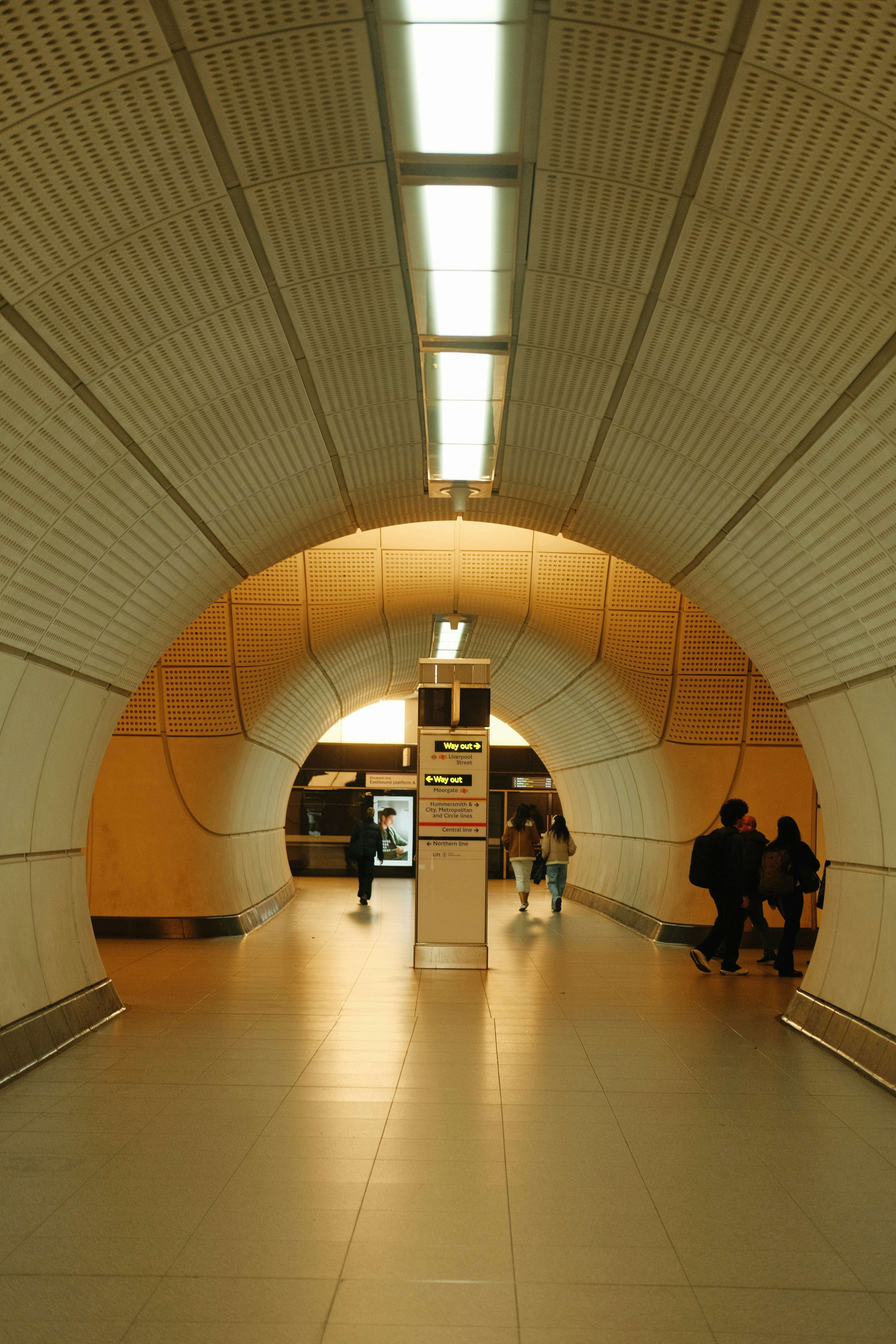 Menschen gingen durch einen hell erleuchteten Tunnel einer U-Bahn-Station.