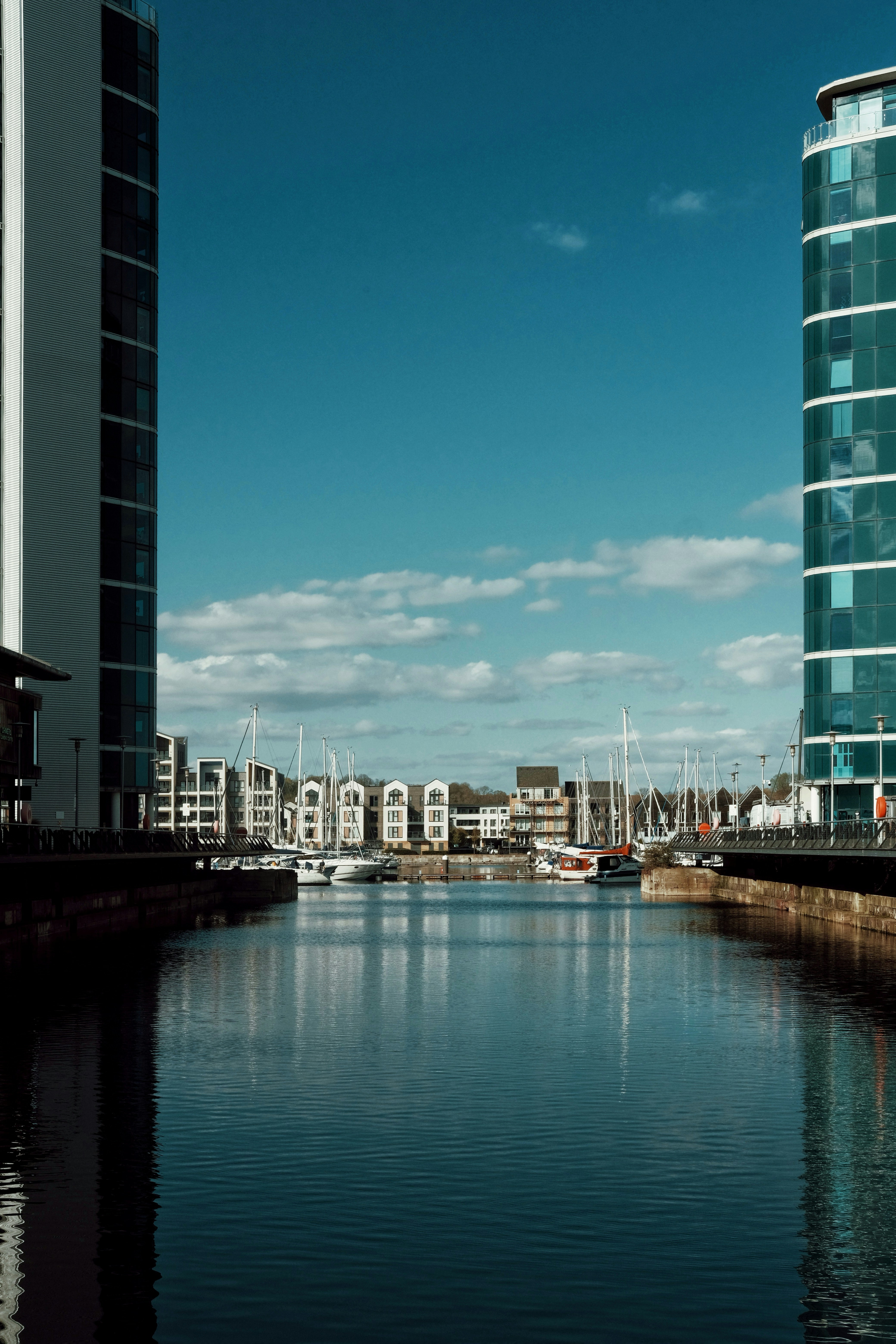 Moderne Gebäude flankieren einen Yachthafen mit Segelbooten unter blauem Himmel
