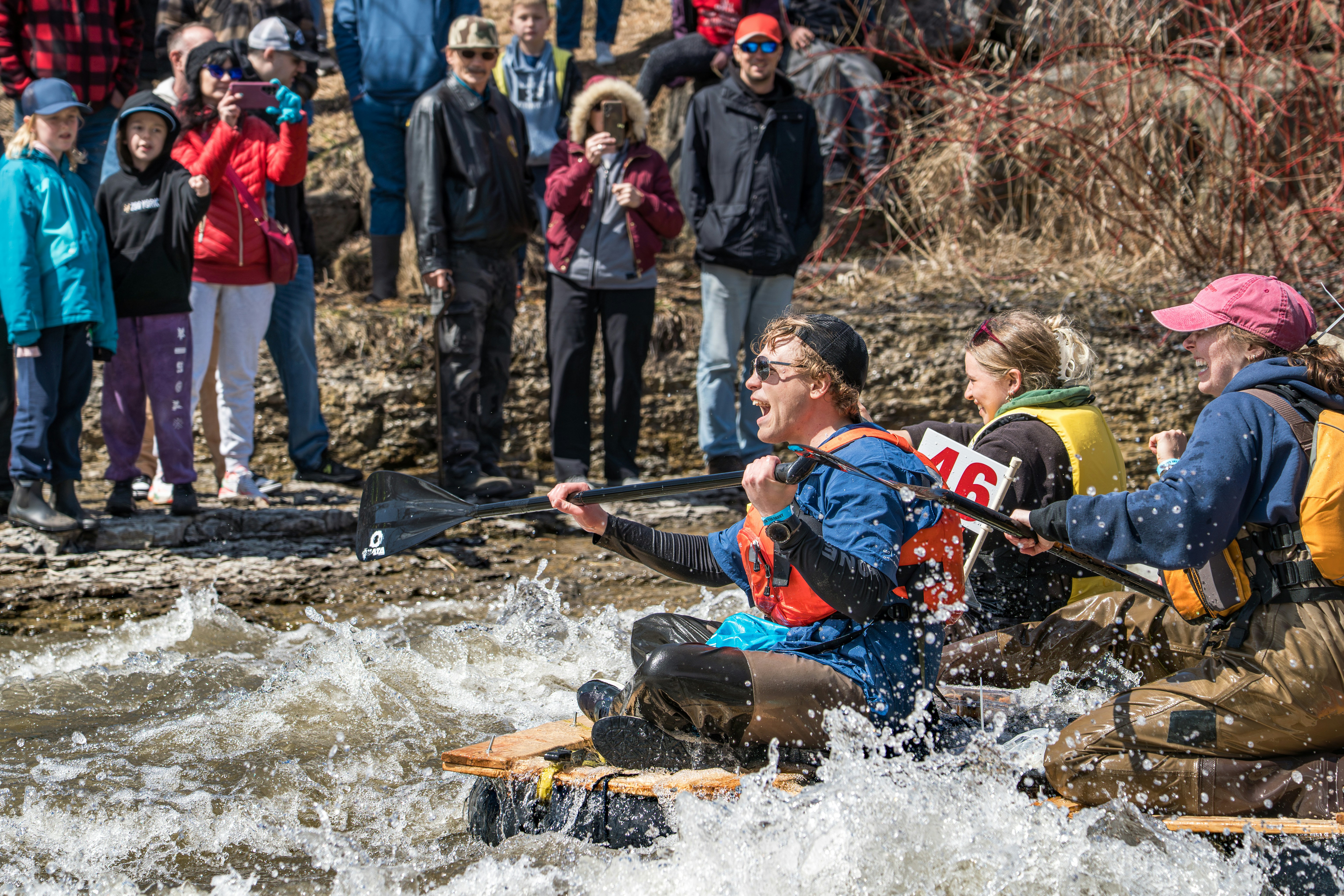 People watch a raft race on a choppy river.