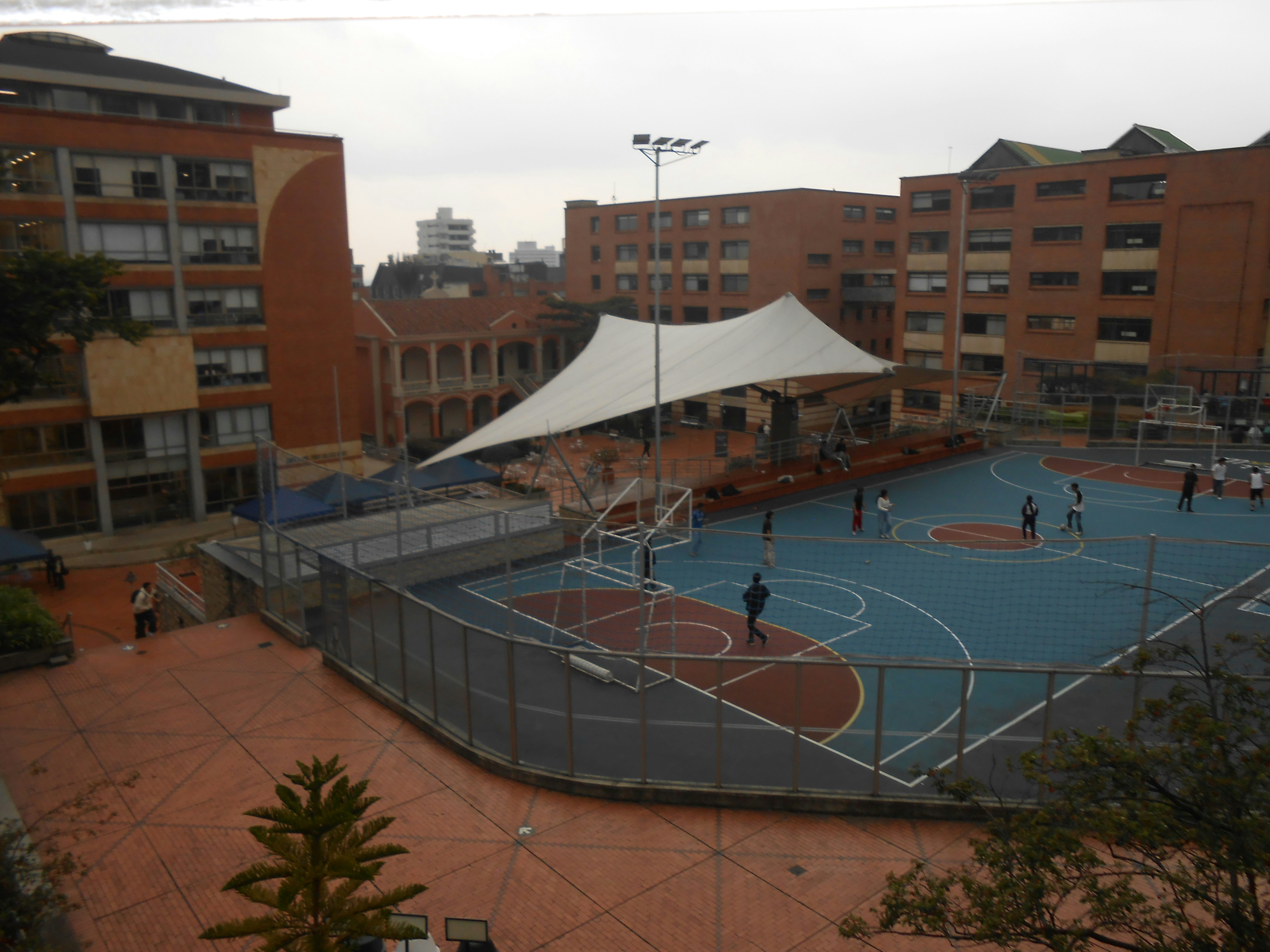 Basketball court with people playing under a large canopy.
