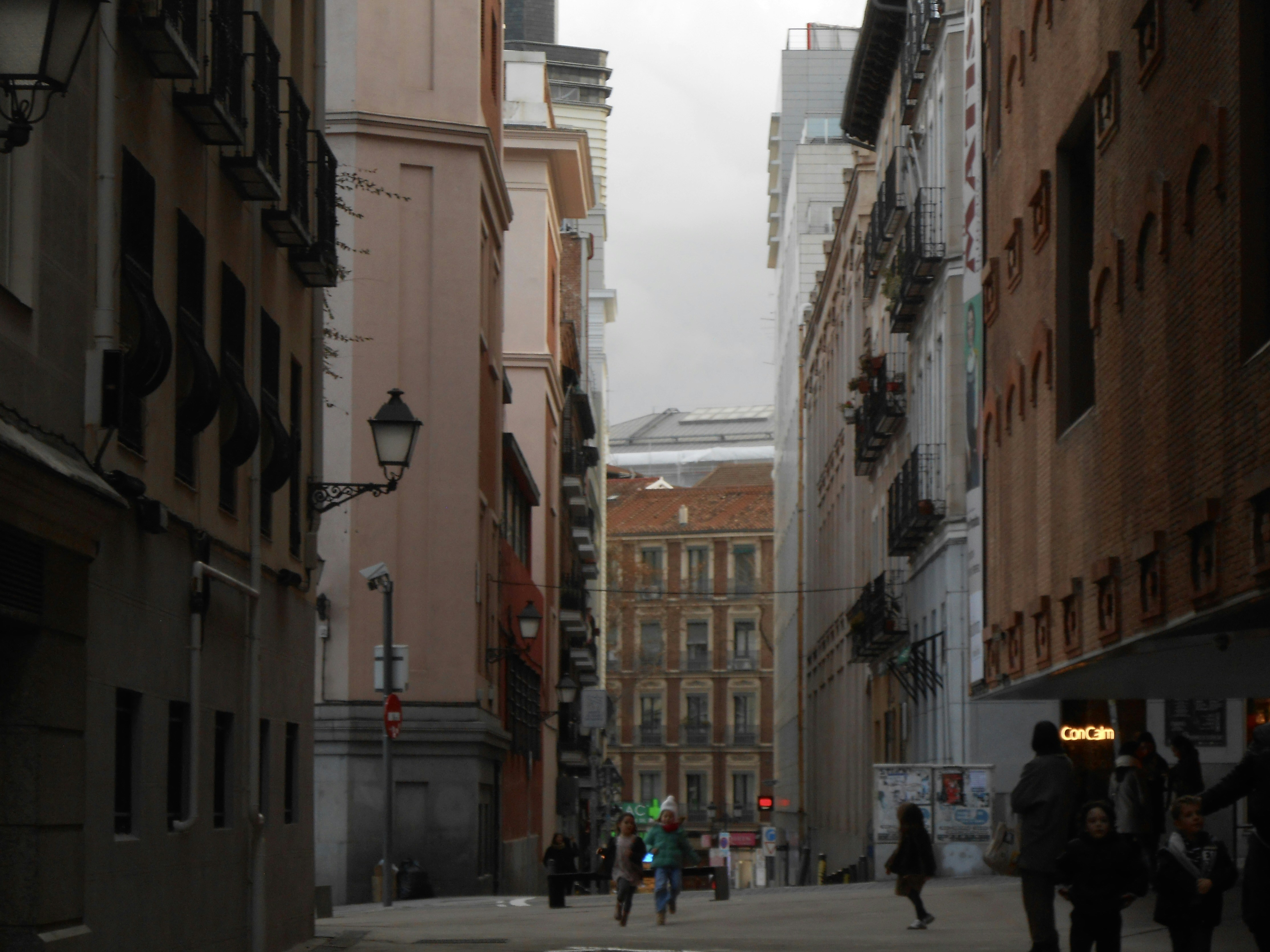 Rua estreita com prédios altos e pessoas andando