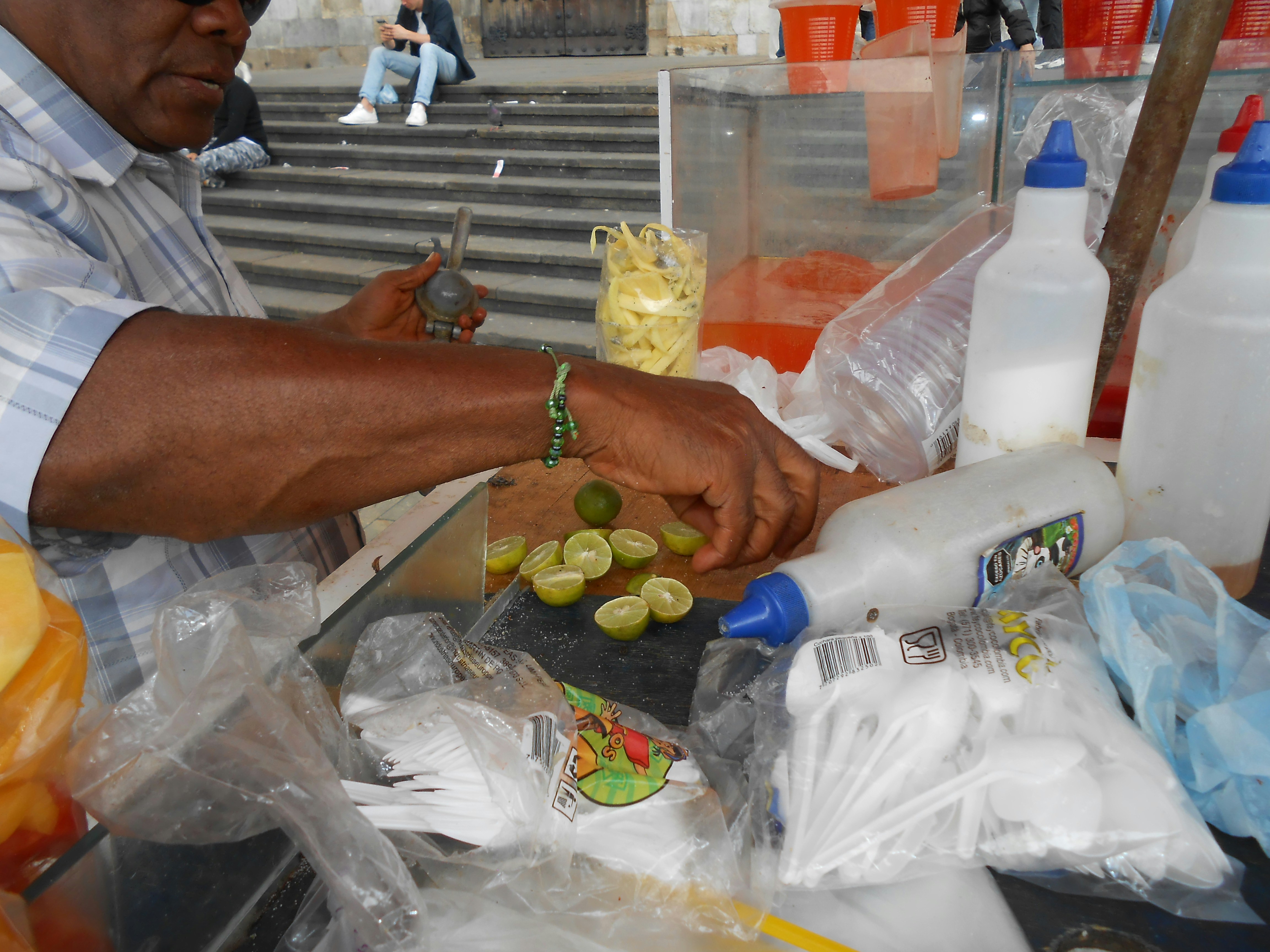 Vendor preparing drinks with limes and condiments.