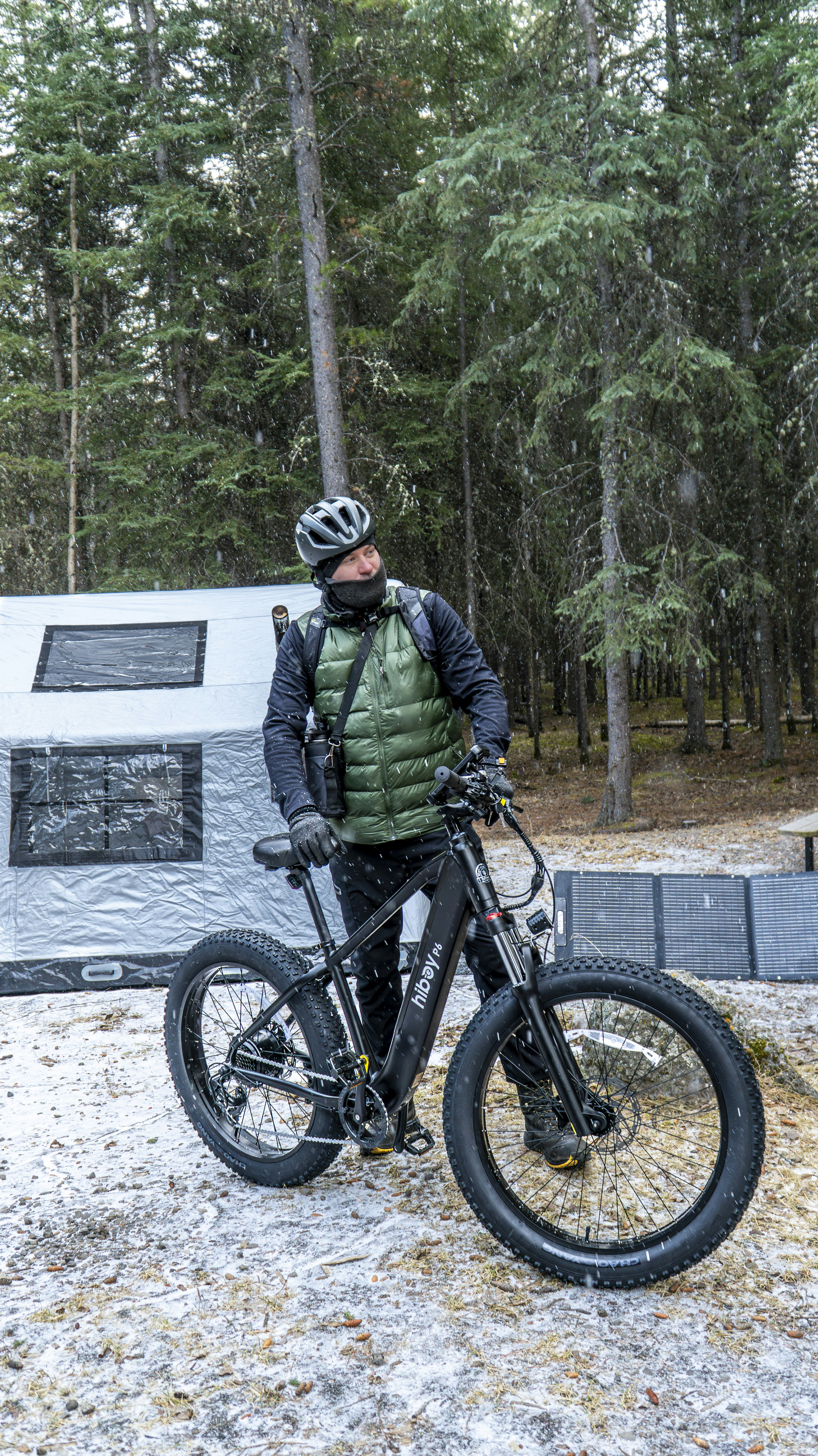 Man with fat tire bike in snowy forest near tent