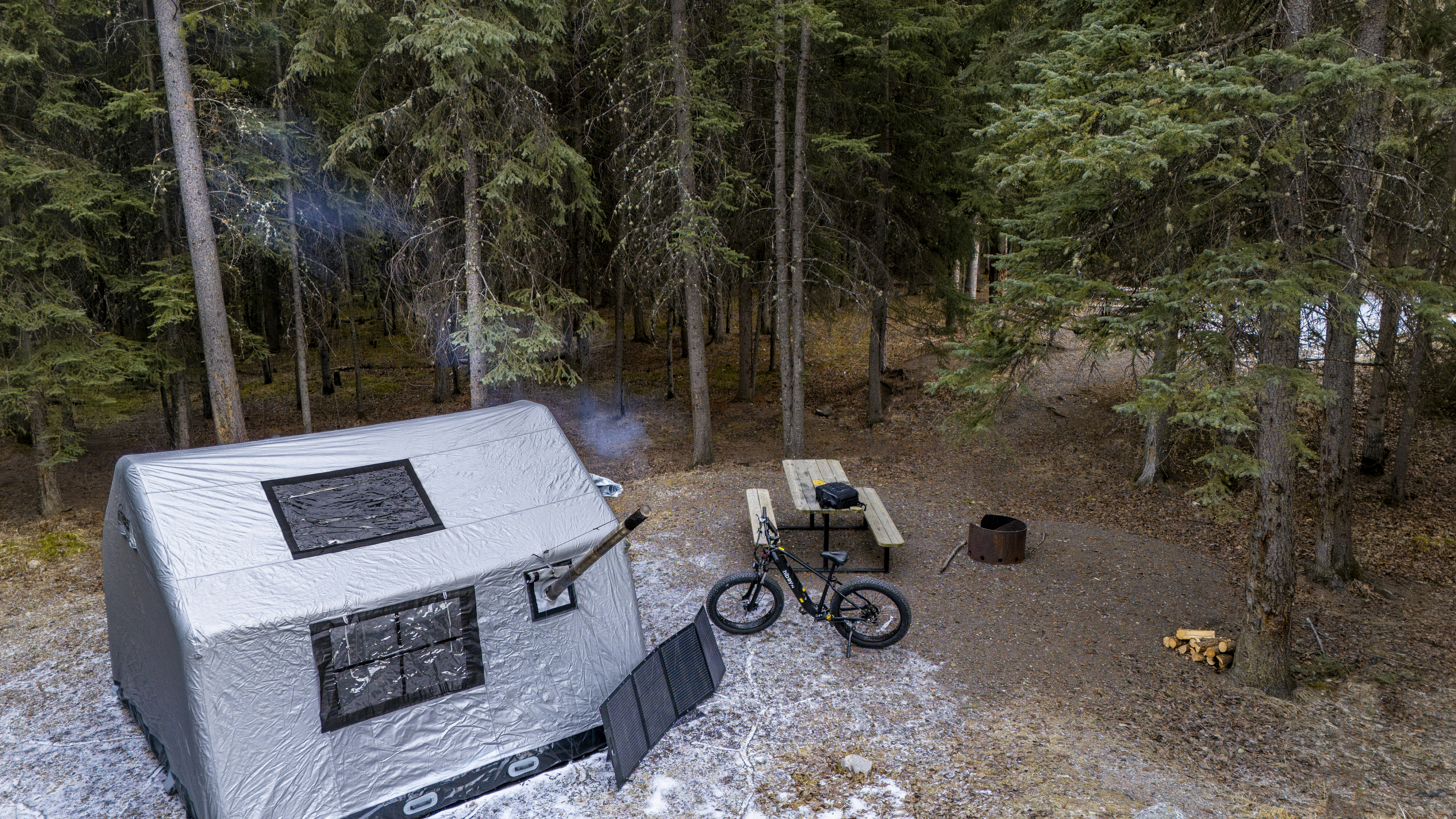 Winter campsite with a tent and picnic table.