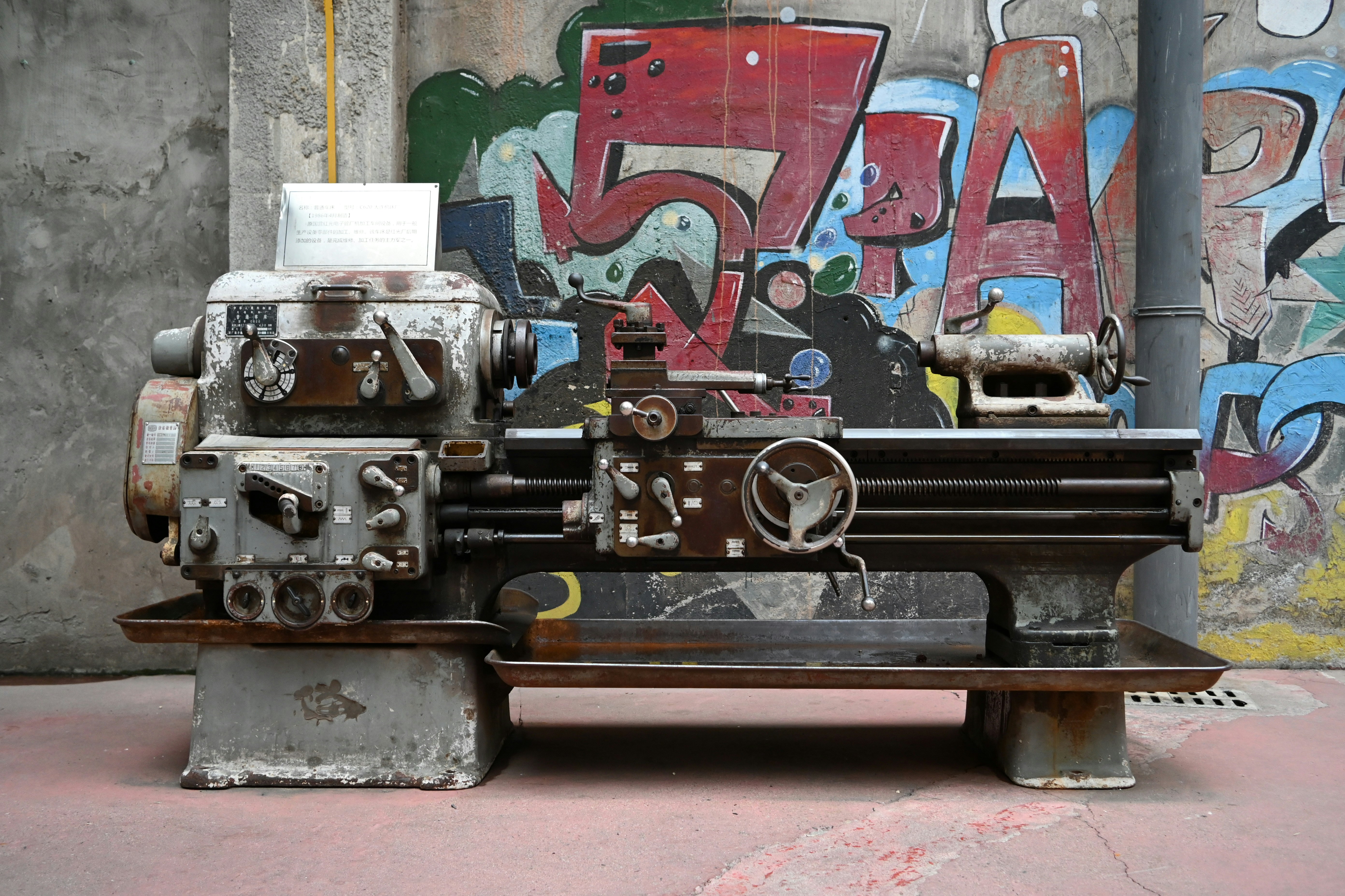 Un torno metálico vintage contra una pared de grafiti.