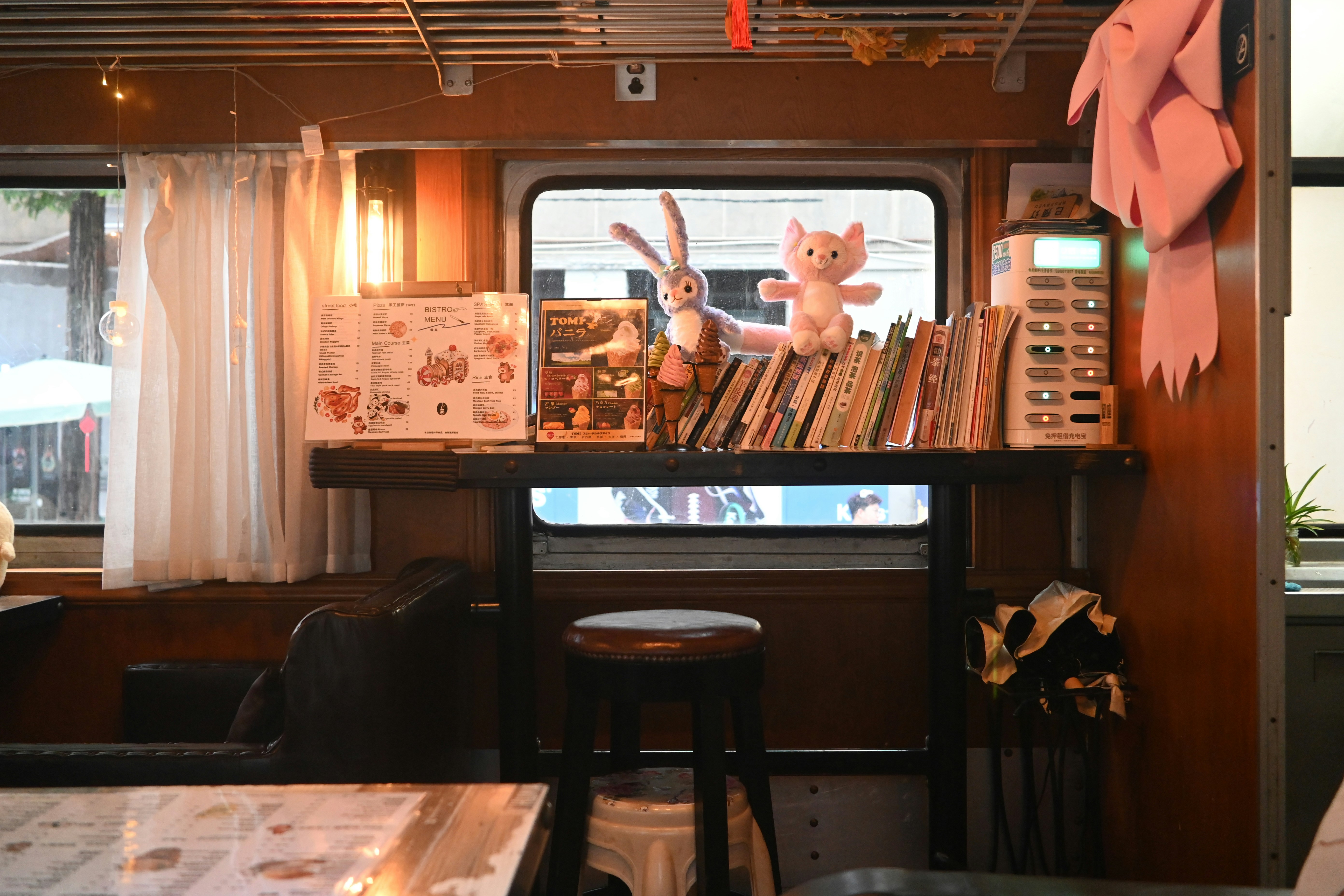 Peluches y libros en una estantería junto a la ventana.