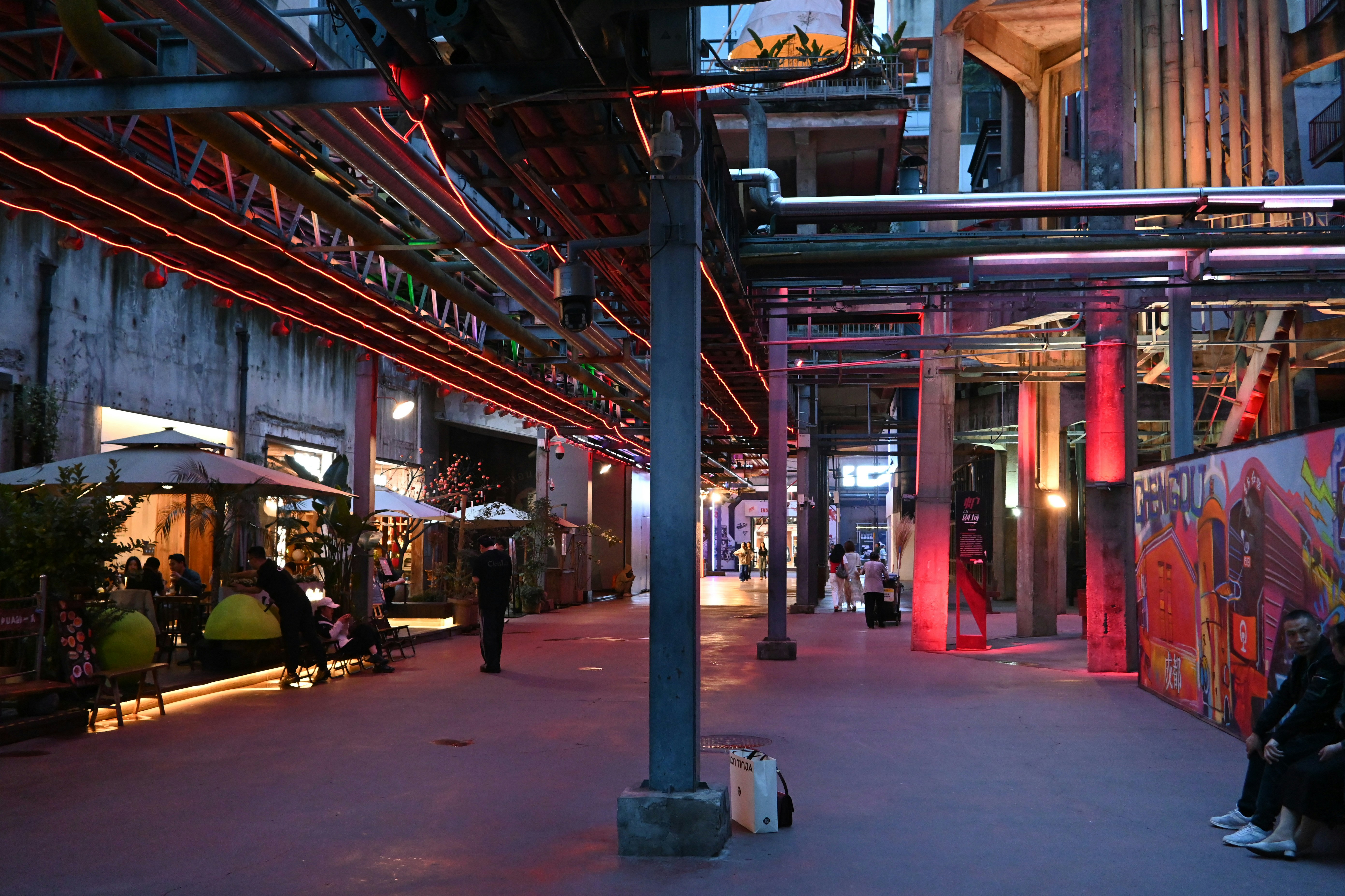 Zona industrial con luces de neón y gente caminando