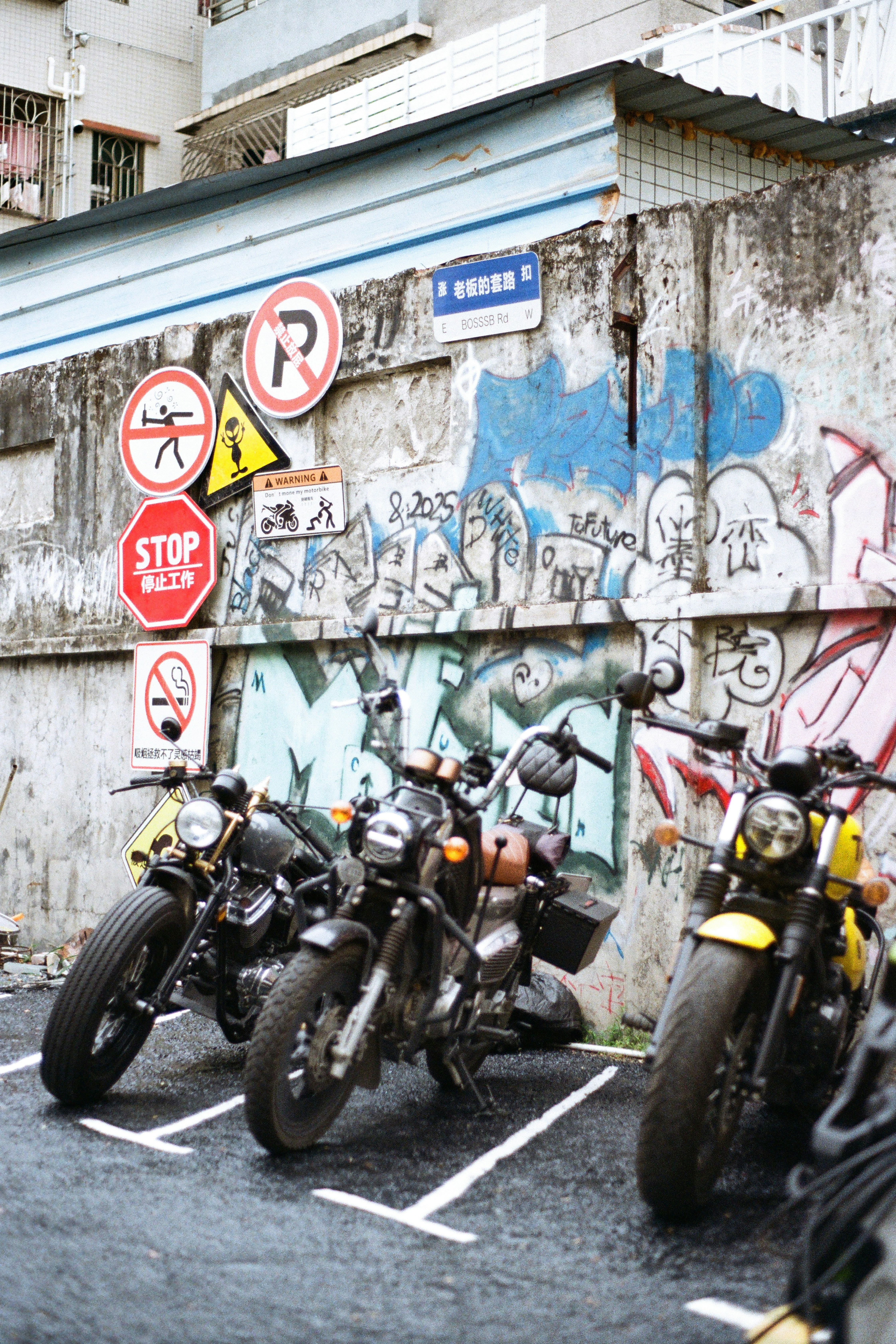 Trois motos garées contre un mur couvert de graffitis.