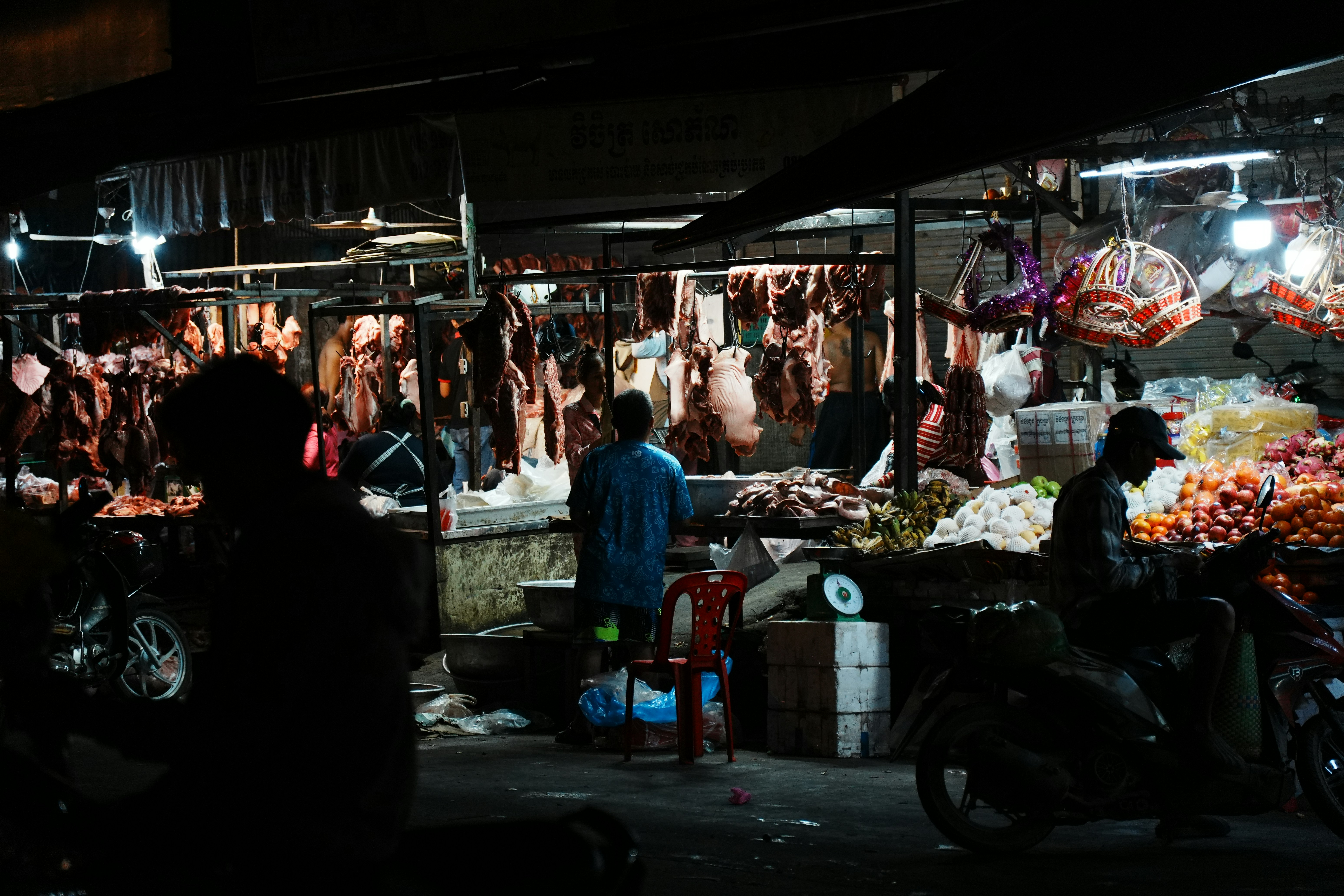 Butchers stall with meat hanging at night.