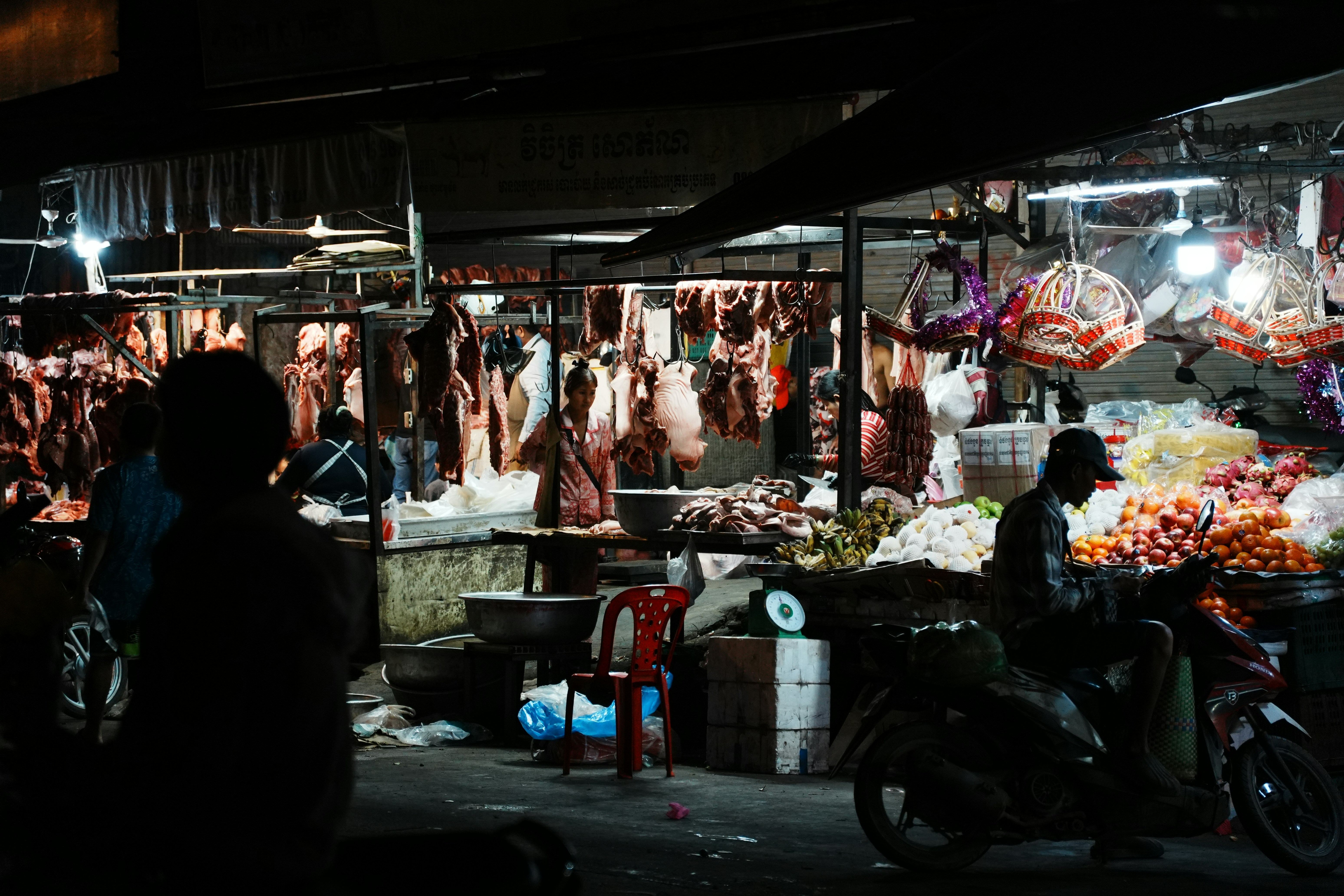 Night market with stalls selling meat and produce.