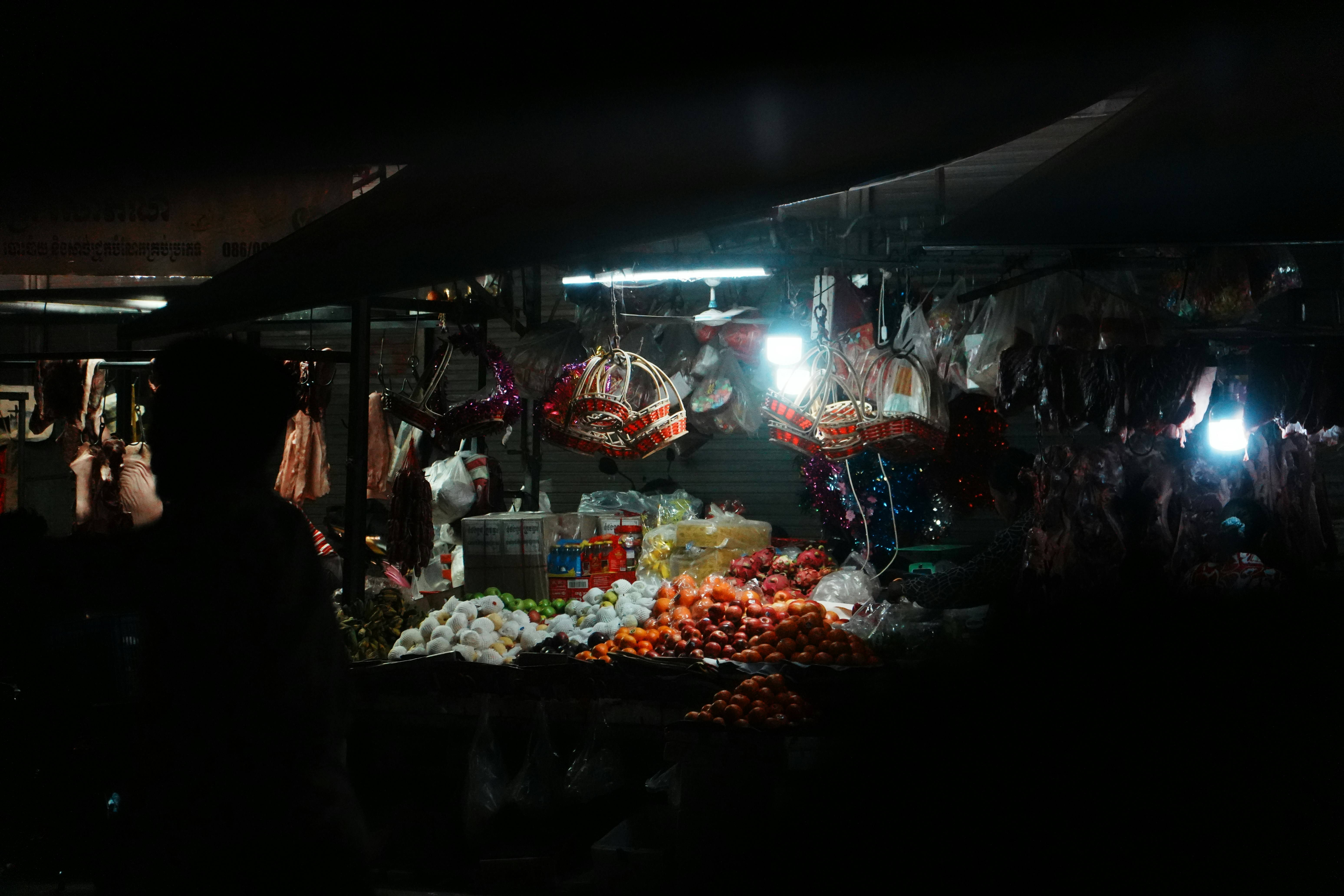 A dimly lit market stall at night with produce.