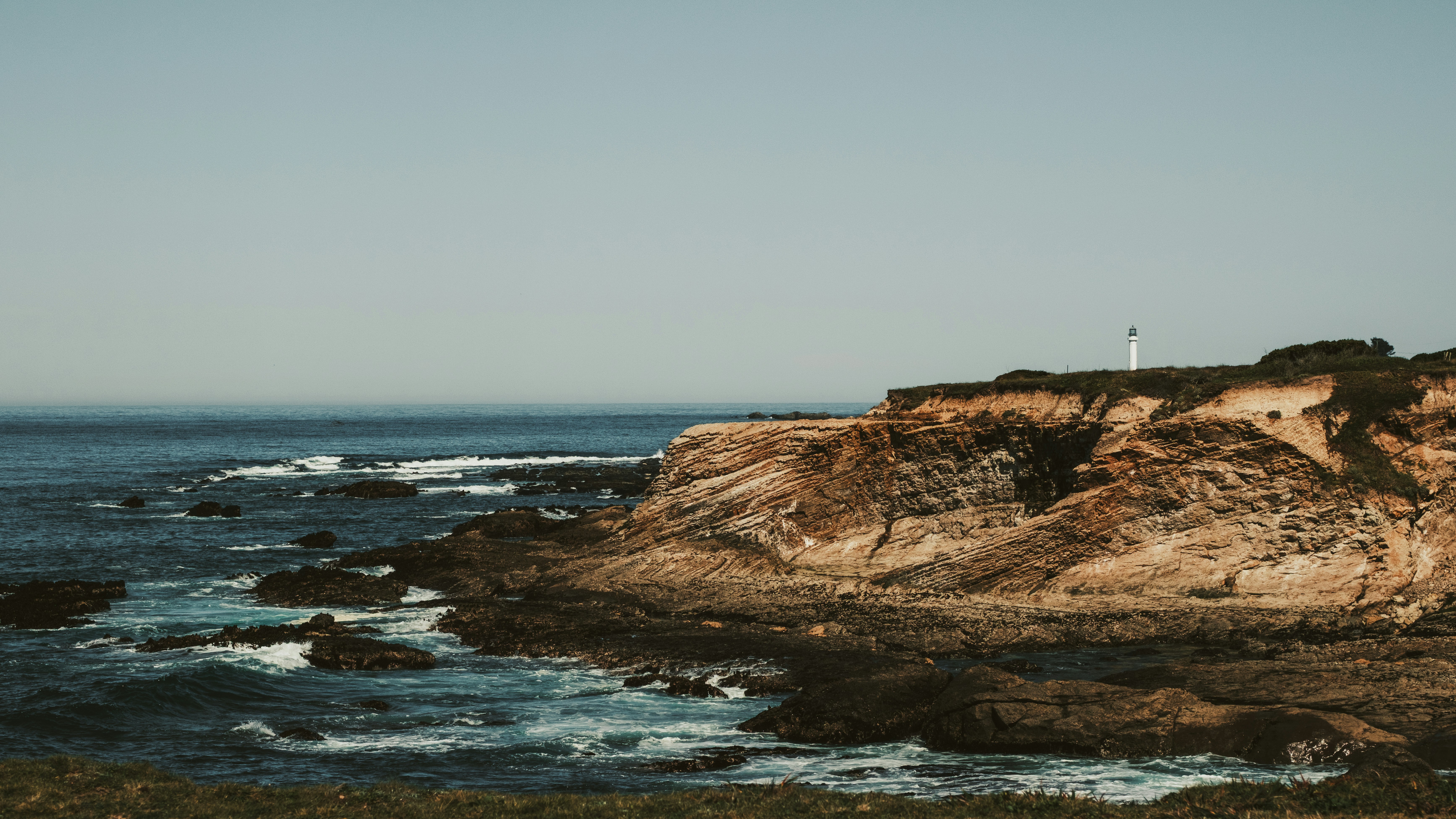 Rocky coastline with a lighthouse on a cliff.