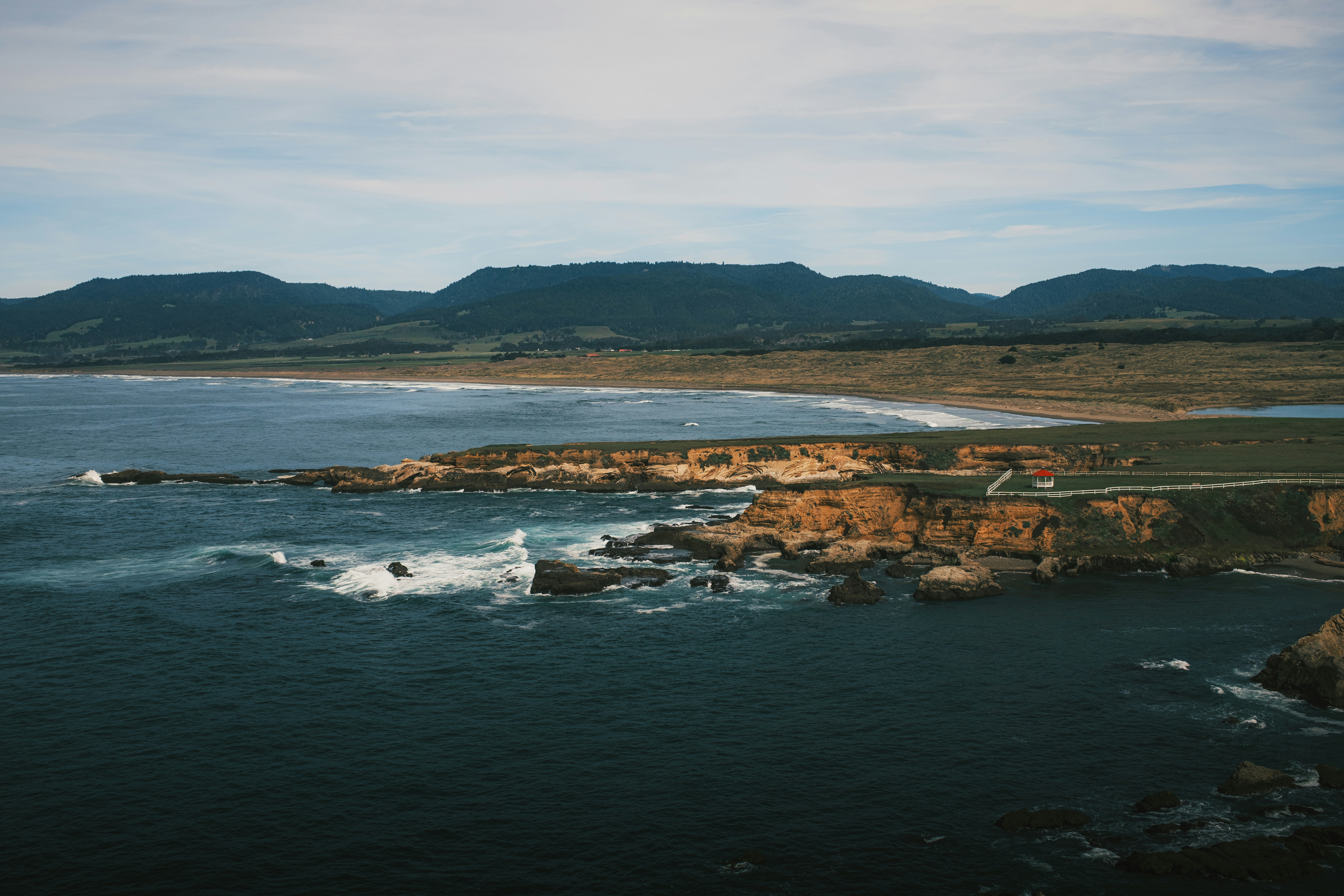 Rocky coastline with ocean waves and distant hills