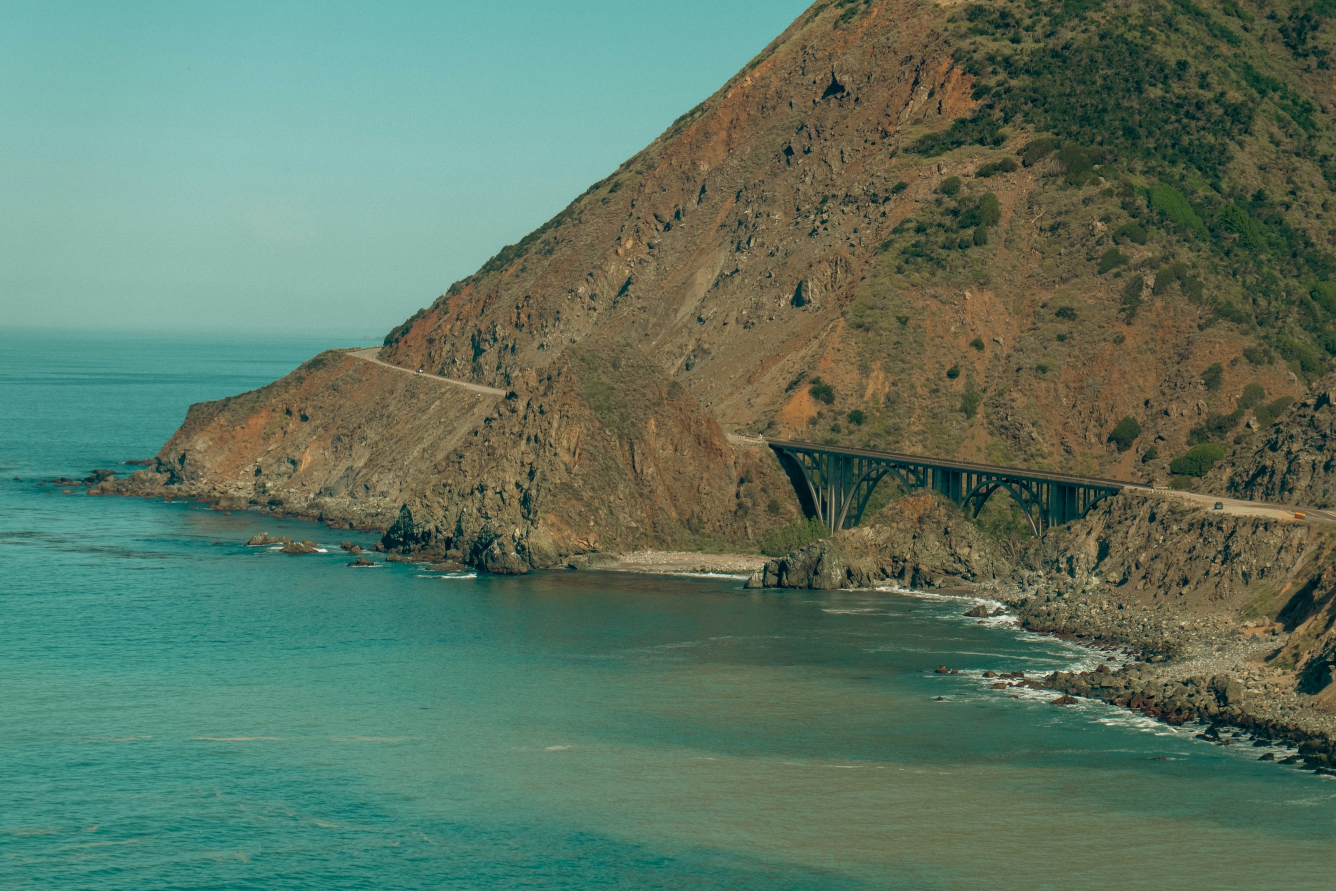 A small wooden boat floating on crystal clear turquoise water near a stone pier