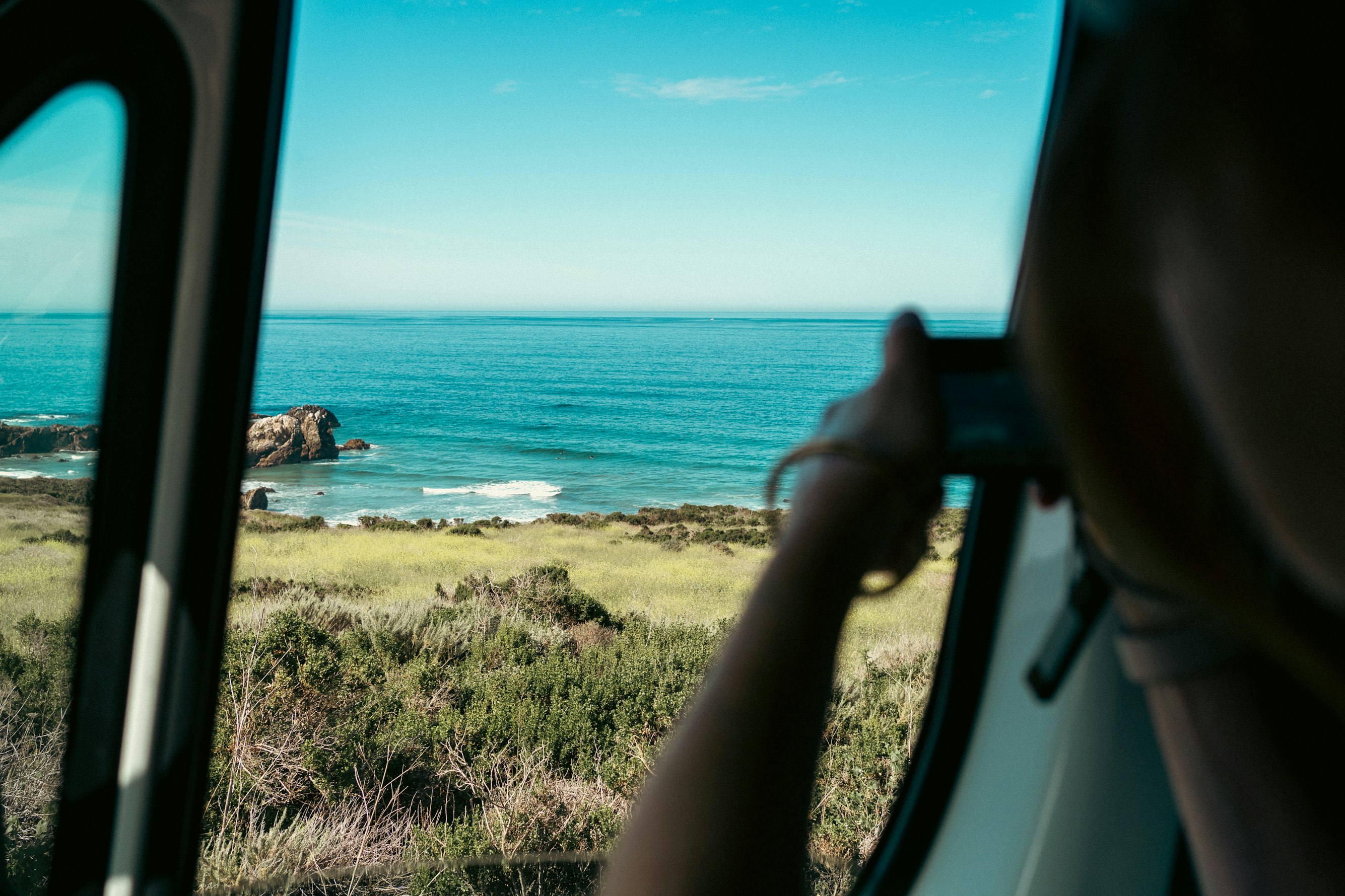 A paved waterfront promenade lined with palm trees overlooking a calm bay