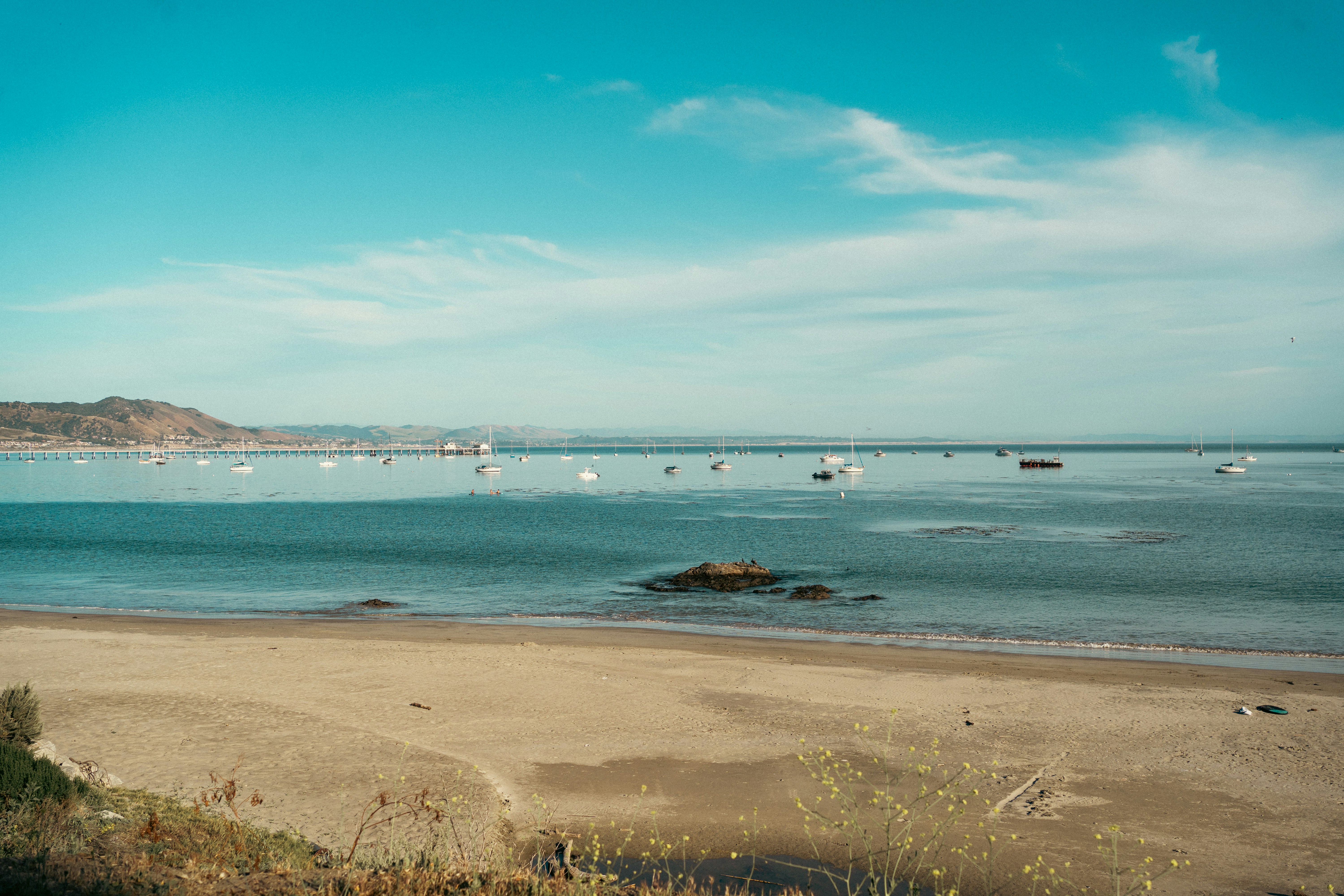 Boats anchored in a calm bay with a sandy beach