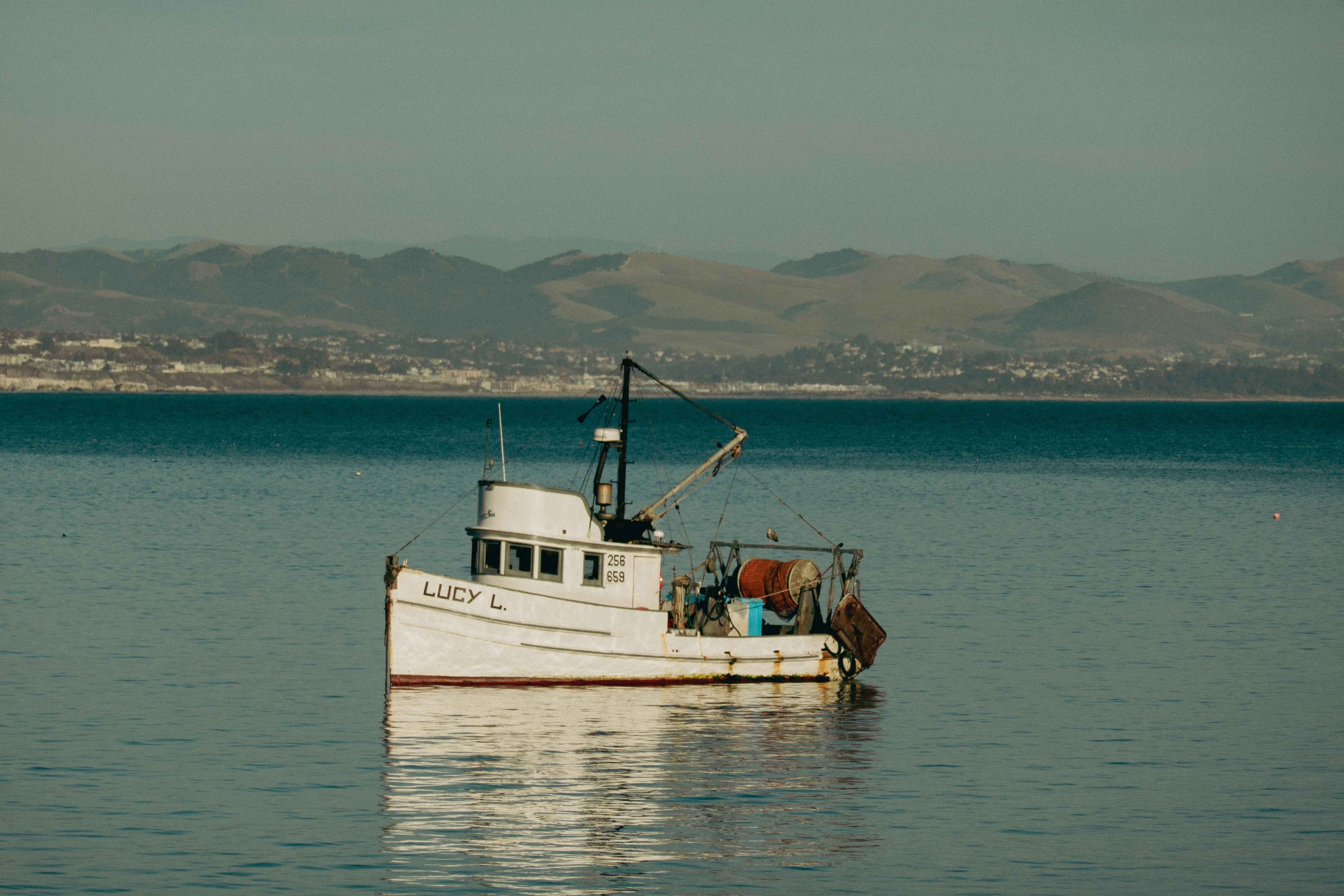 Ein kleines weißes Fischerboot treibt auf ruhigem Wasser.