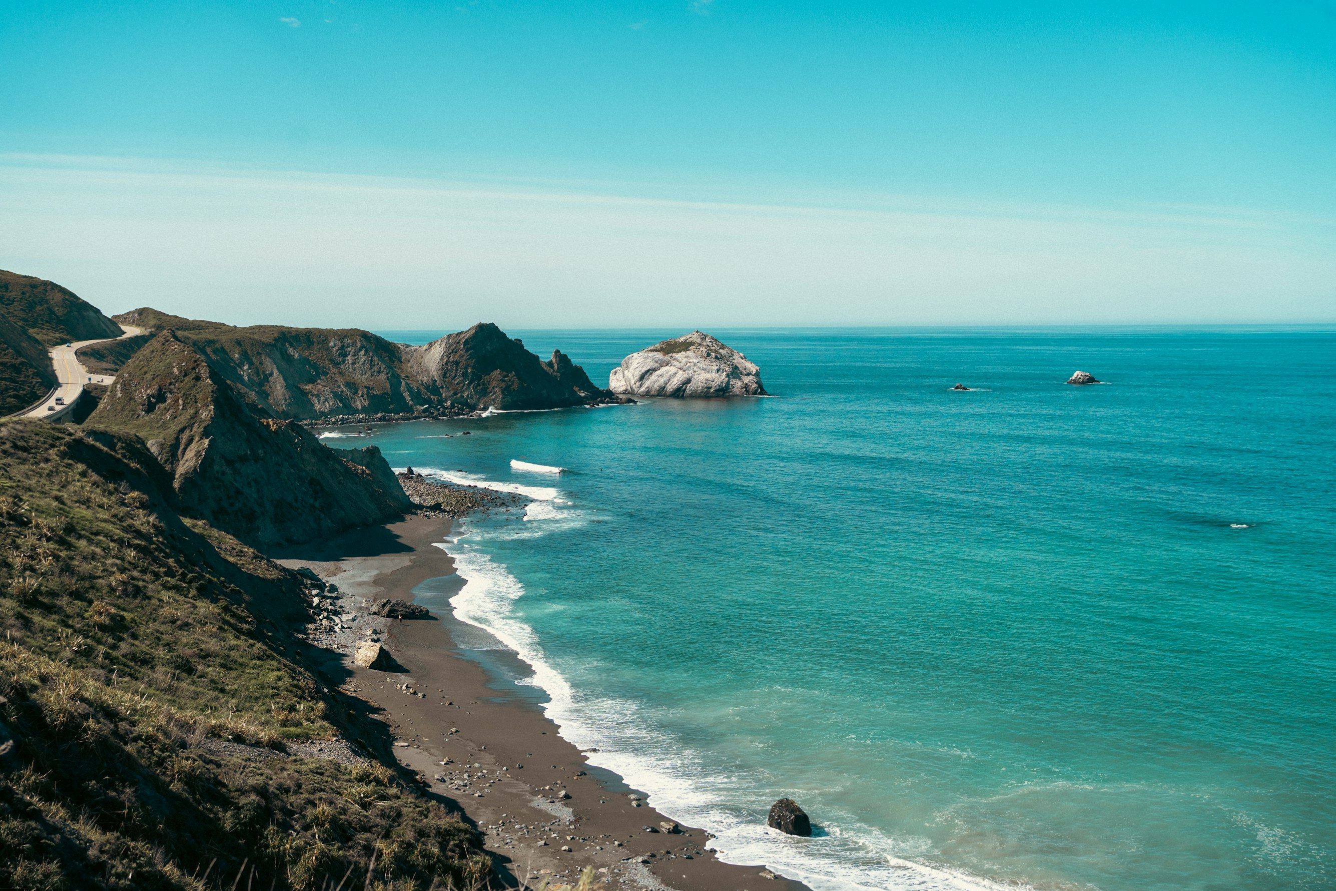 Empty outdoor restaurant tables and chairs on a stone terrace overlooking the ocean