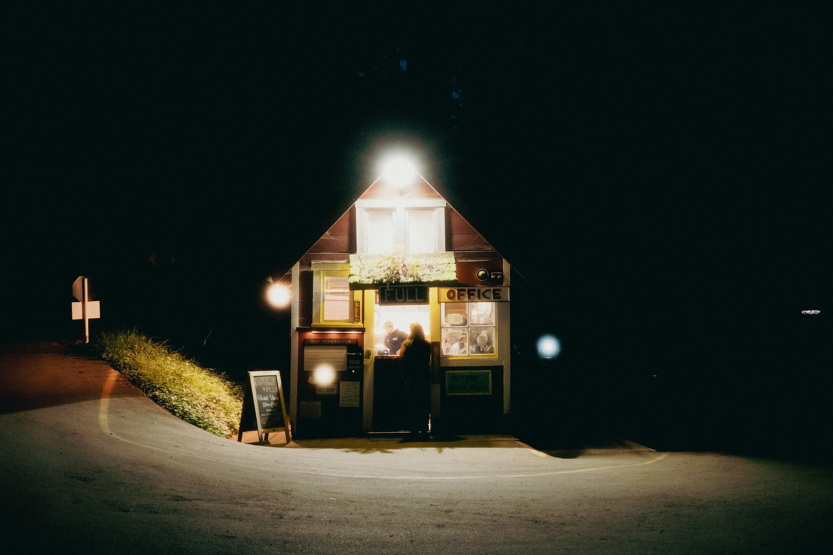 Looking down over terracotta roof tiles toward a bright blue bay and lush greenery
