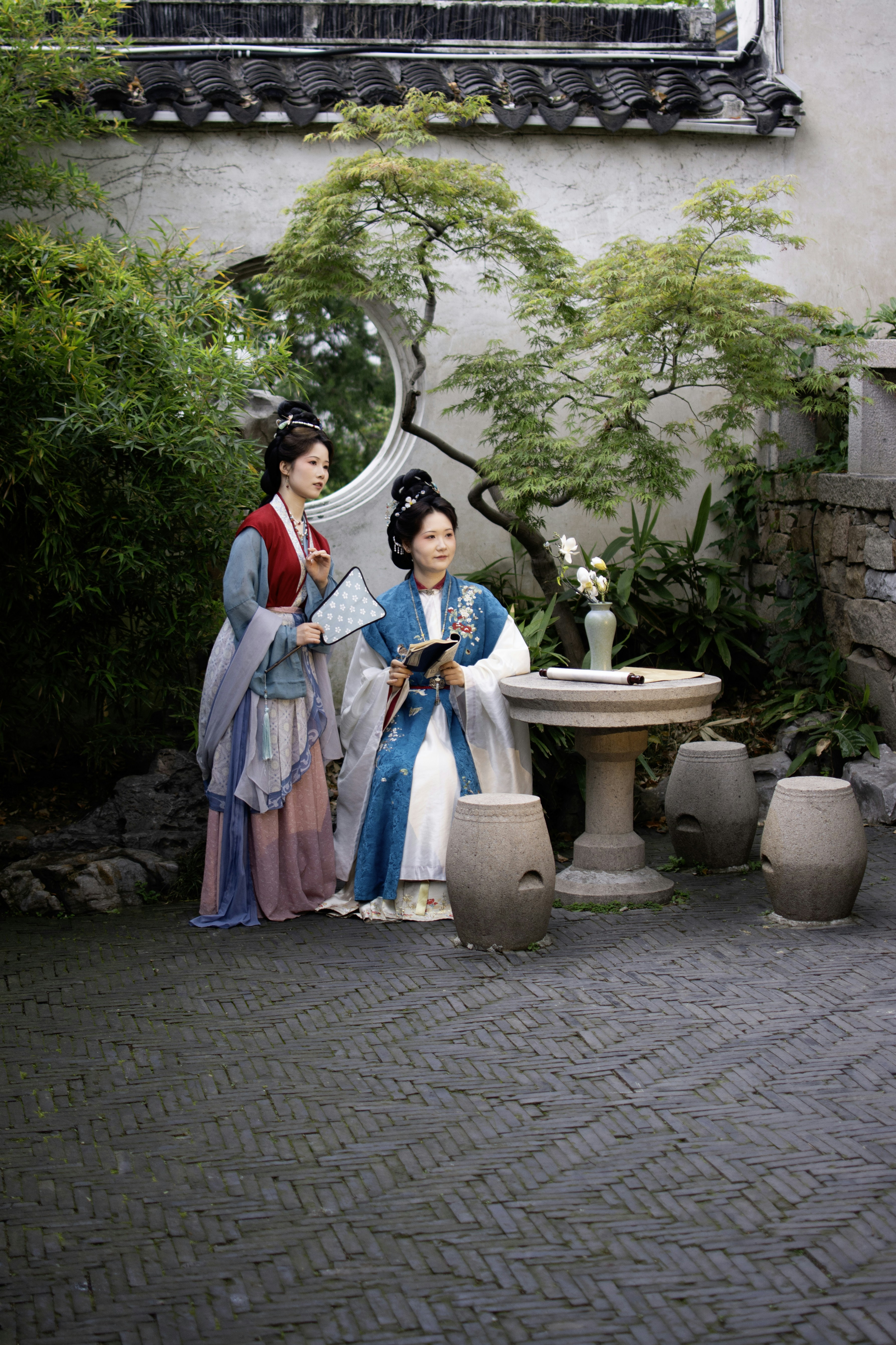 Deux femmes en vêtements traditionnels chinois dans un jardin.