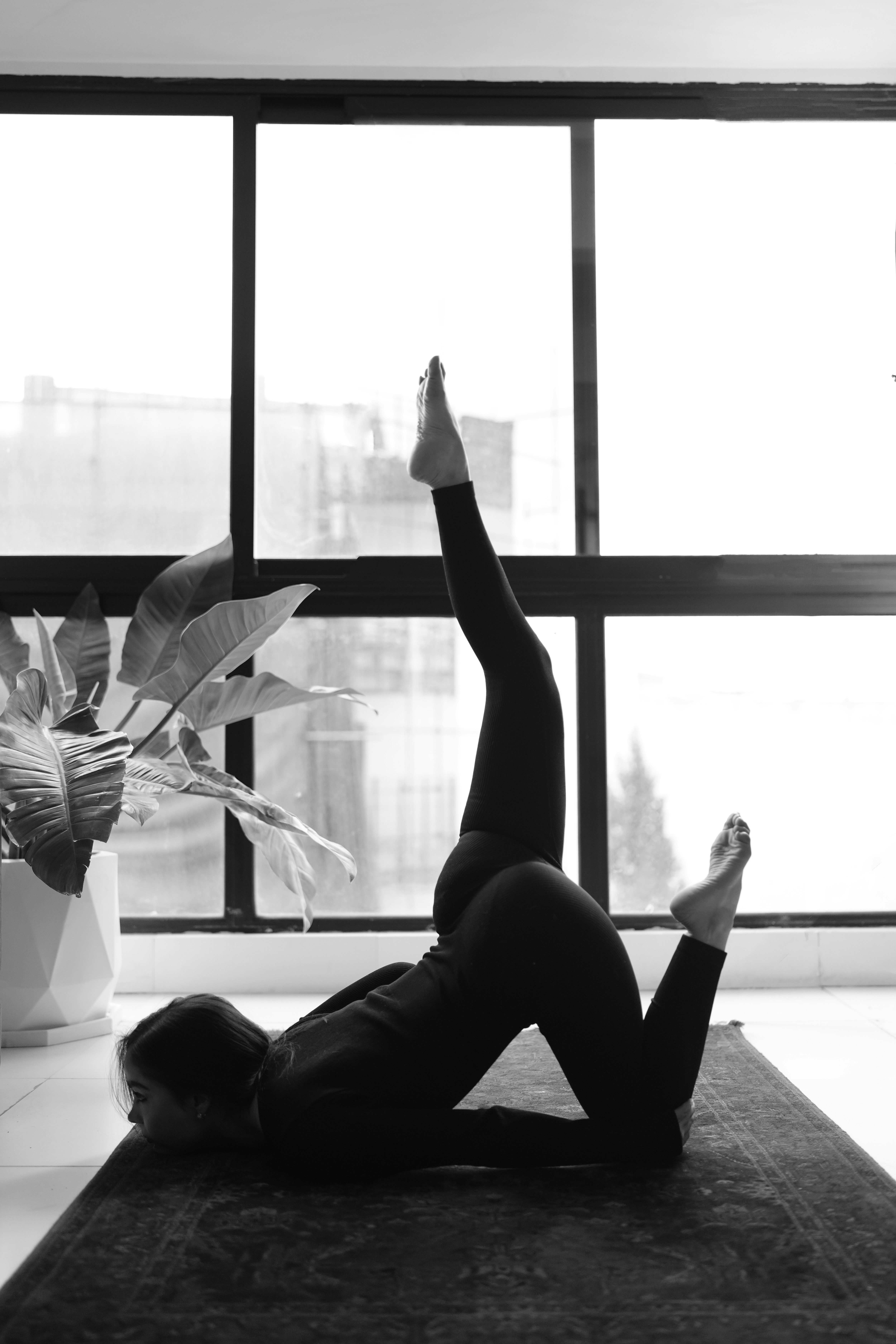 Frau praktiziert Yoga auf einer Matte drinnen.