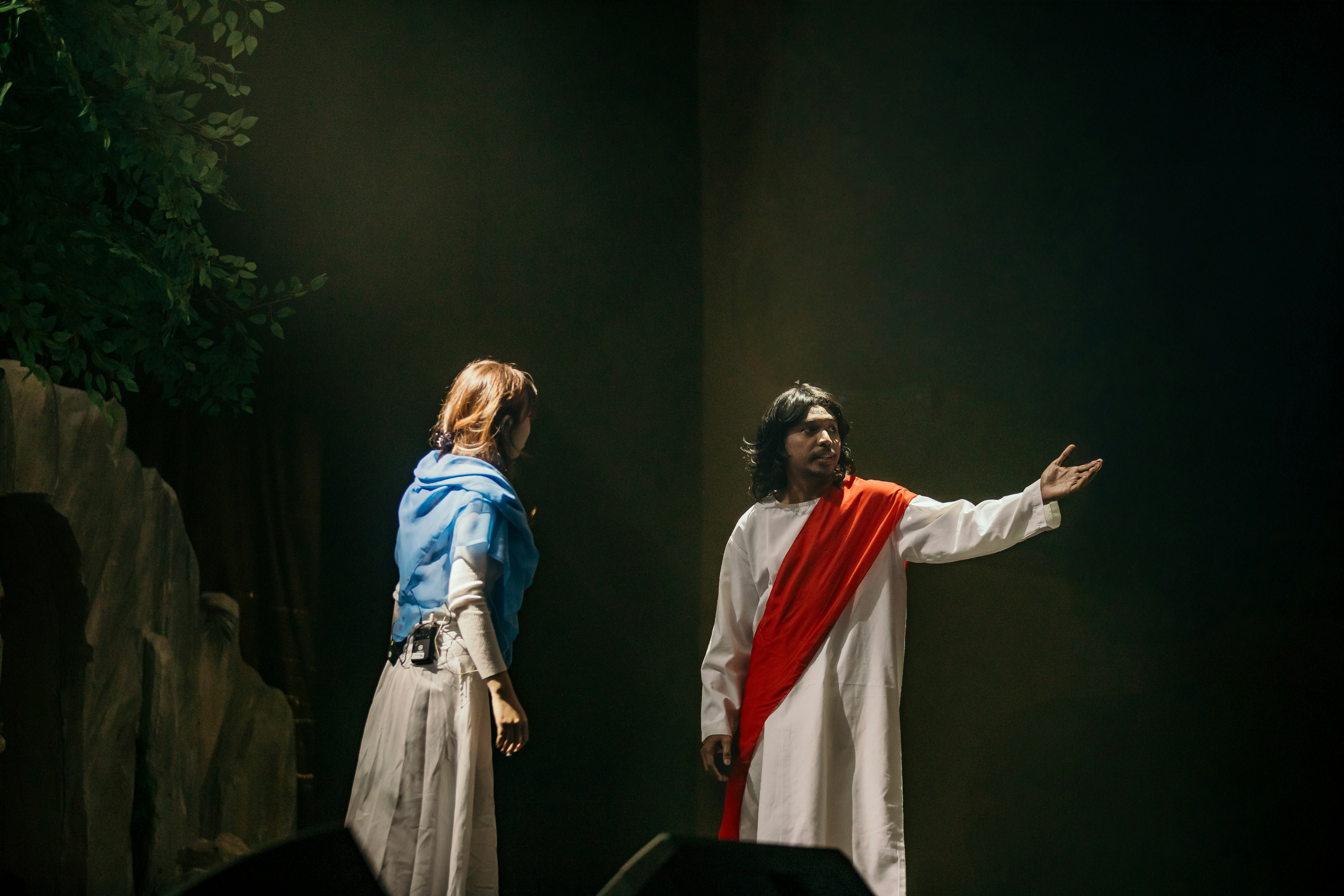 Two people in costume on a dimly lit stage.