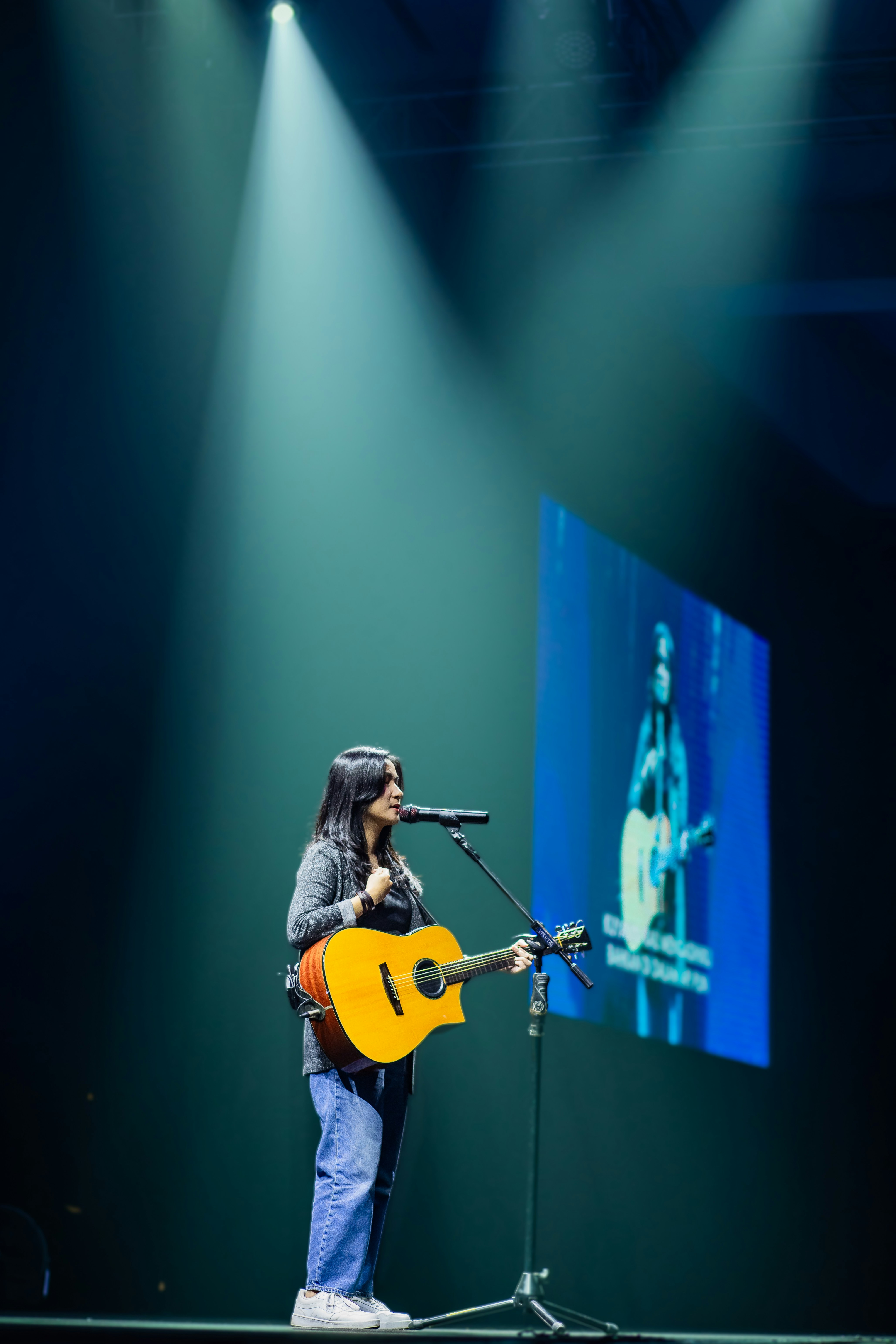 Wanita bermain gitar dan bernyanyi di atas panggung