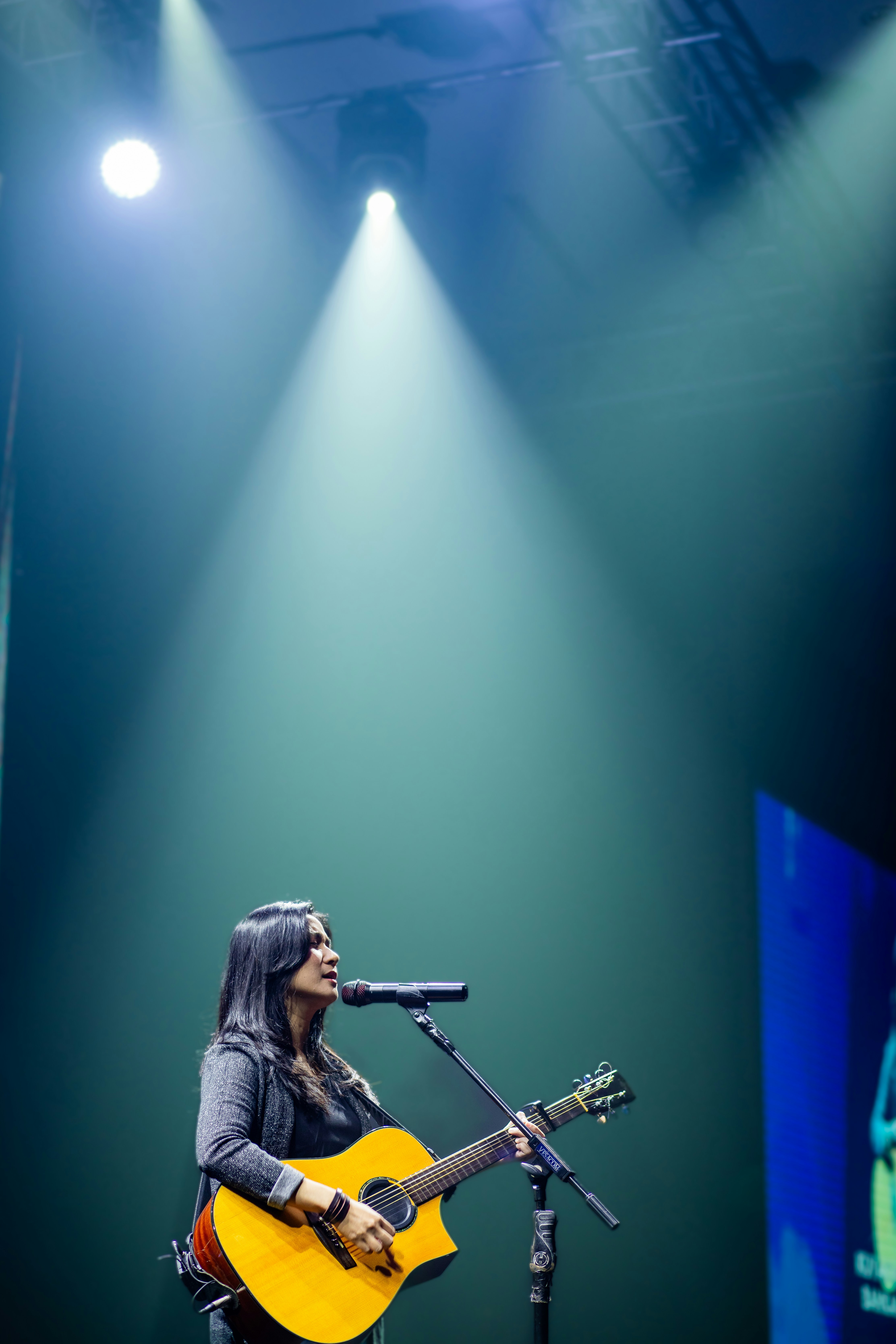 Wanita bermain gitar dan bernyanyi di atas panggung
