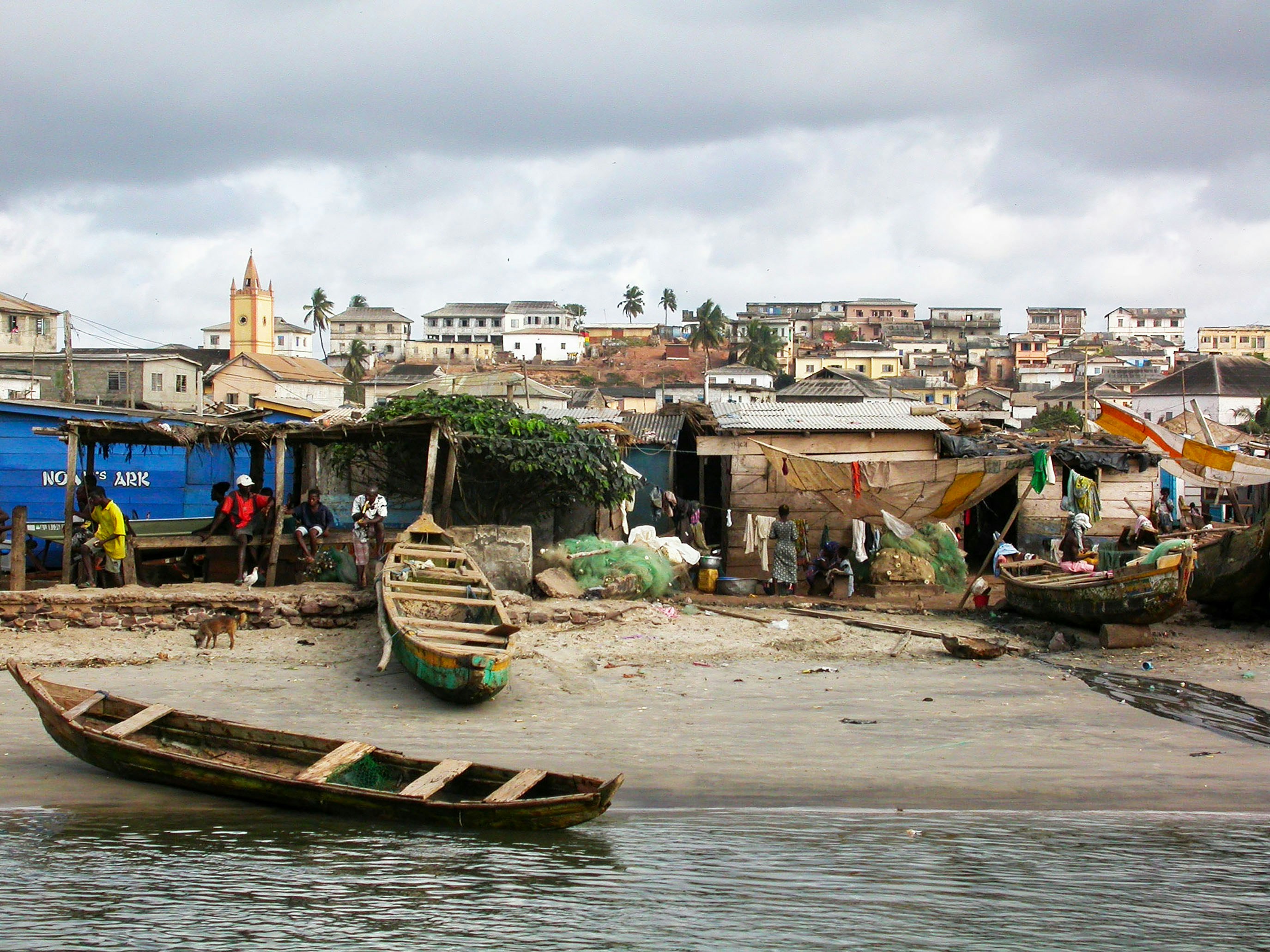 Fishing village with boats on sandy shore and rocky shore