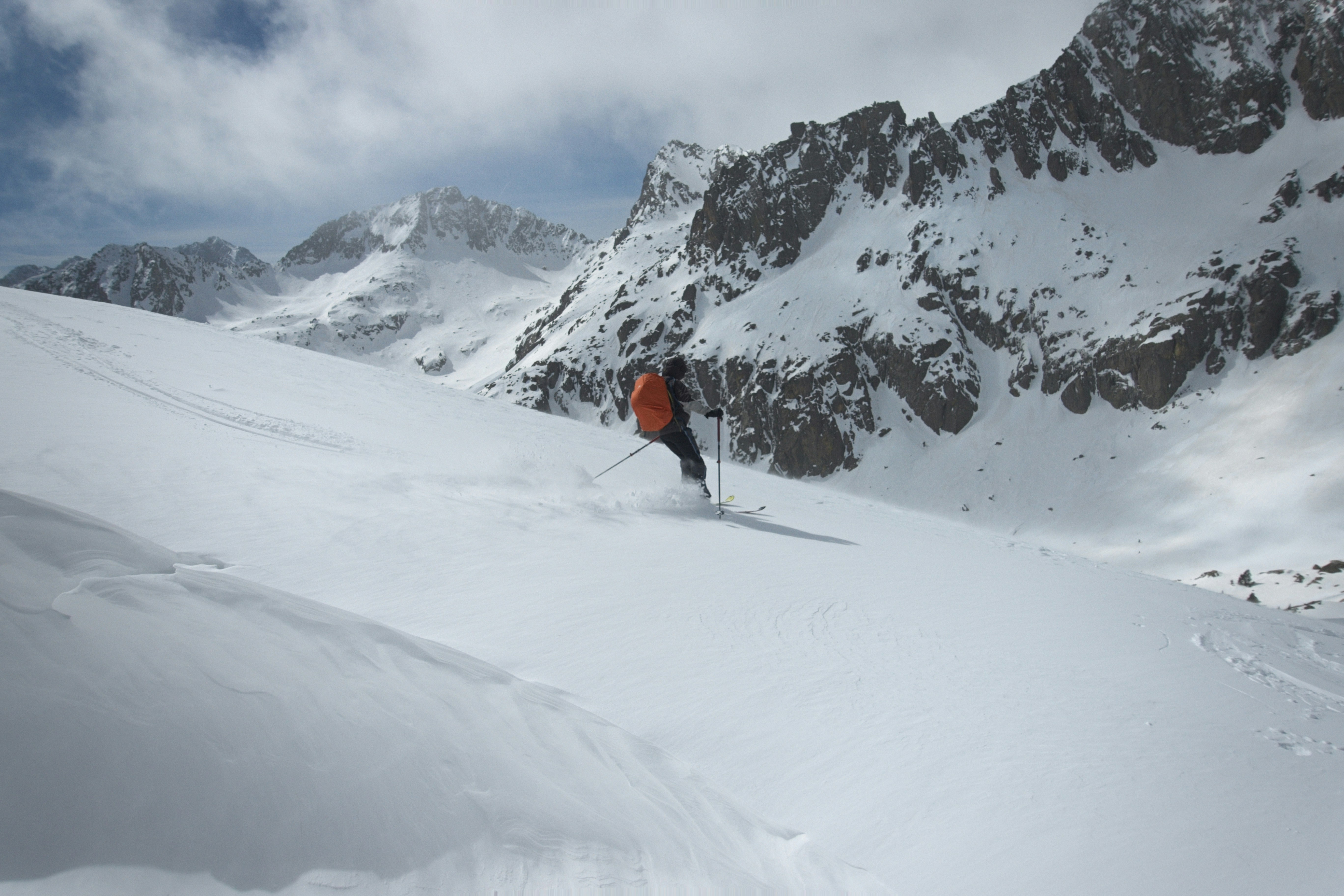 Ein Skifahrer steigt einen verschneiten Berghang hinab.