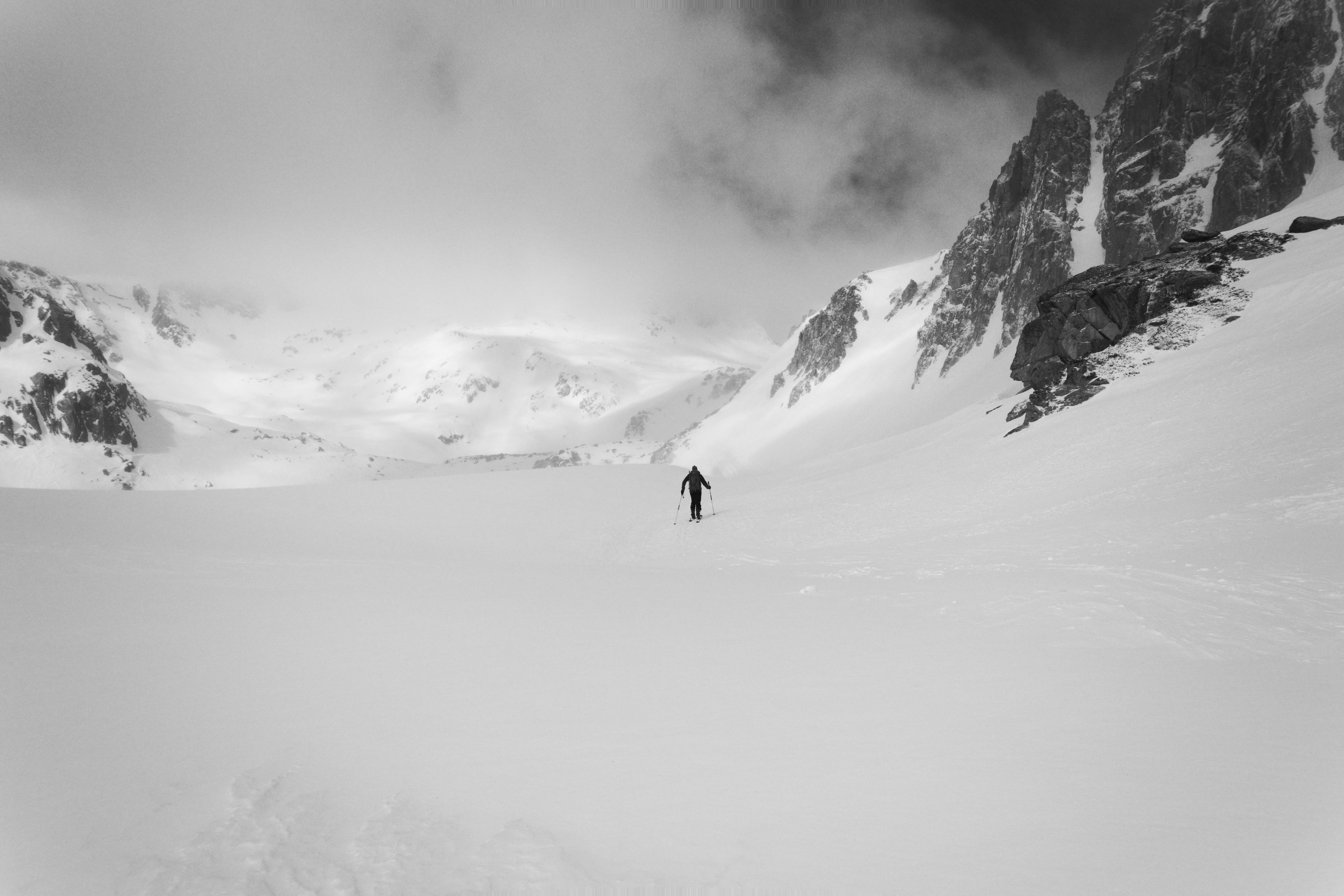 Ein einzelner Skifahrer durchquert eine weite, verschneite Berglandschaft.