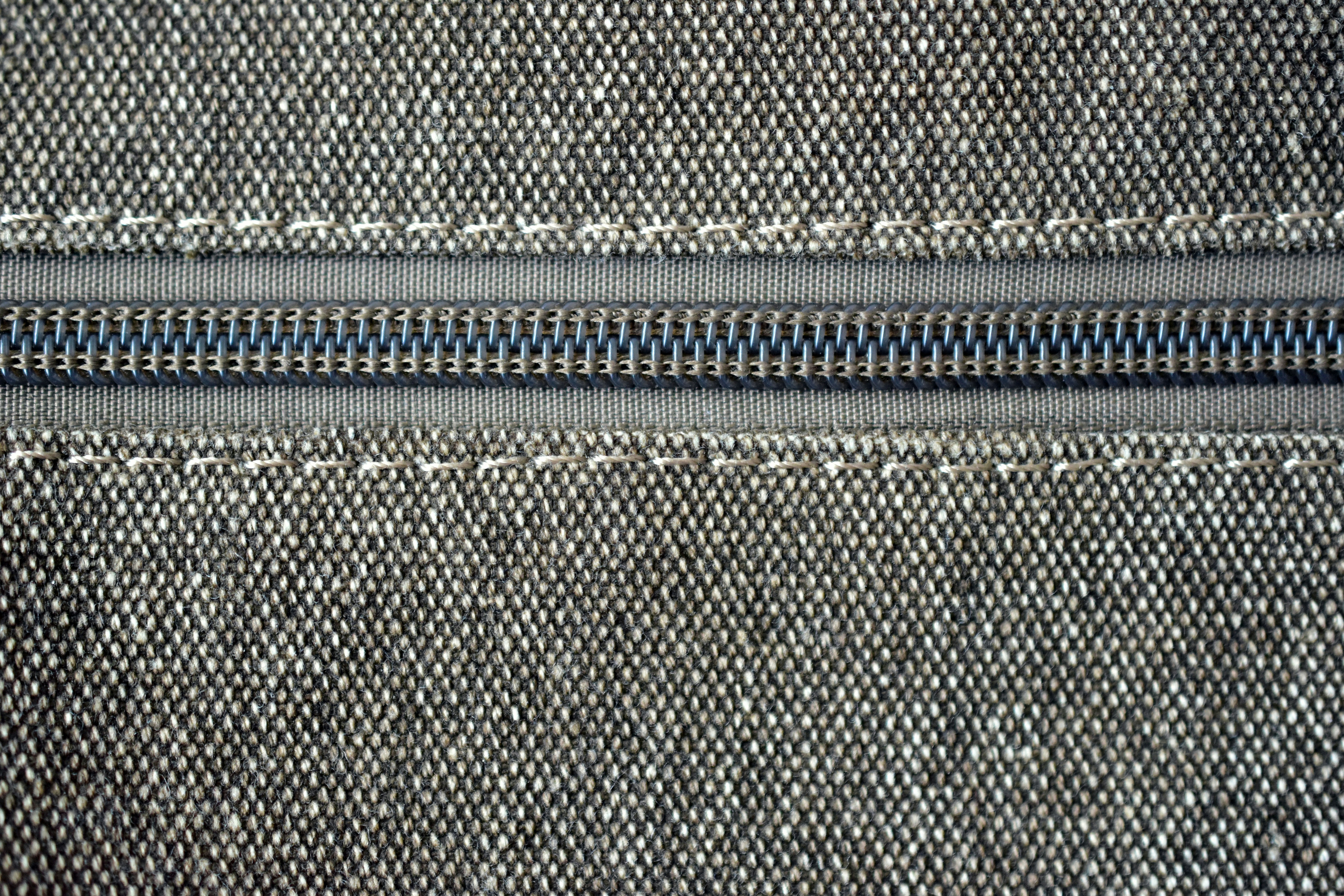 Primer plano de una cremallera gris sobre tela con costuras blancas