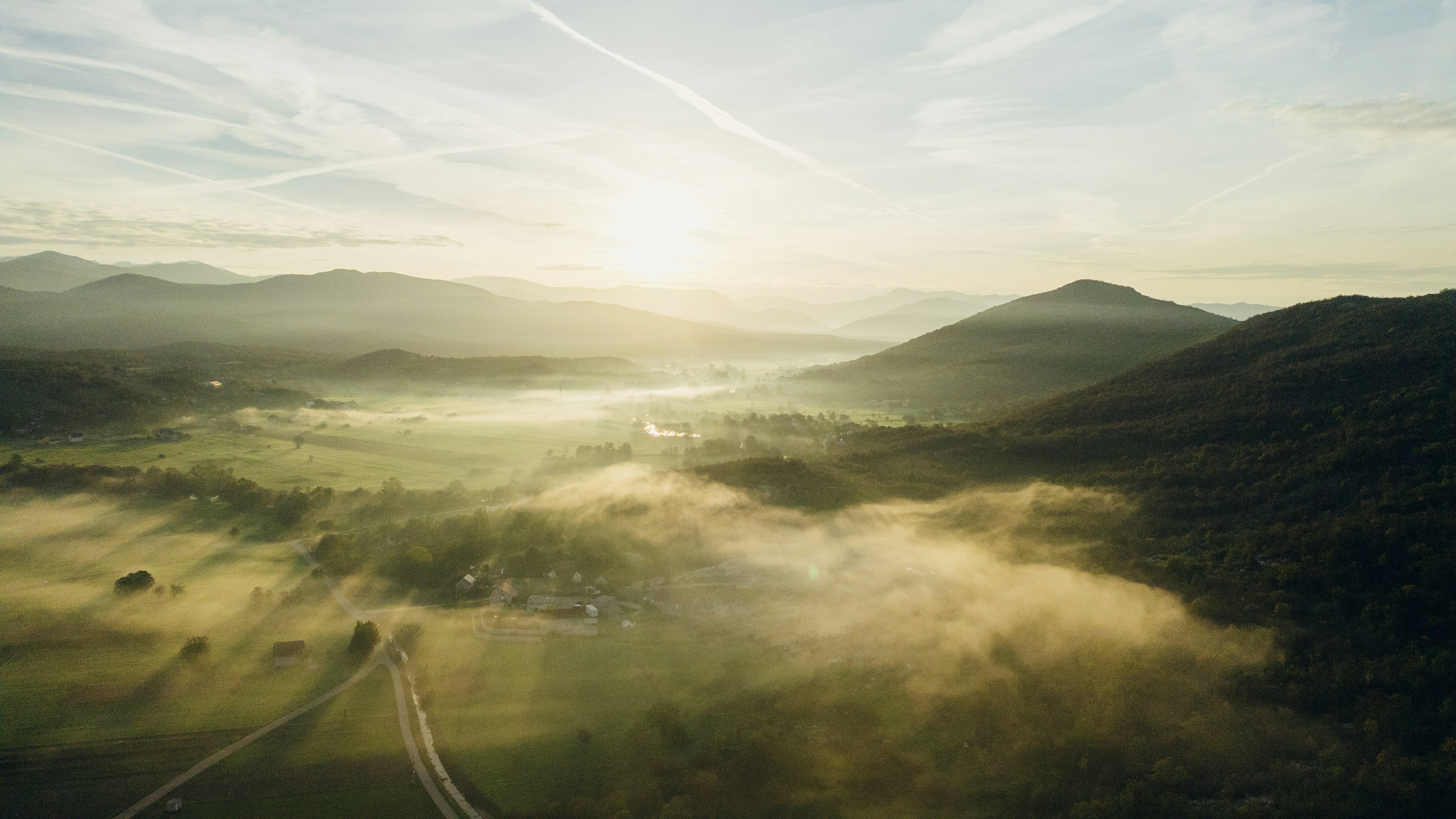 Valle brumoso con colinas onduladas al amanecer