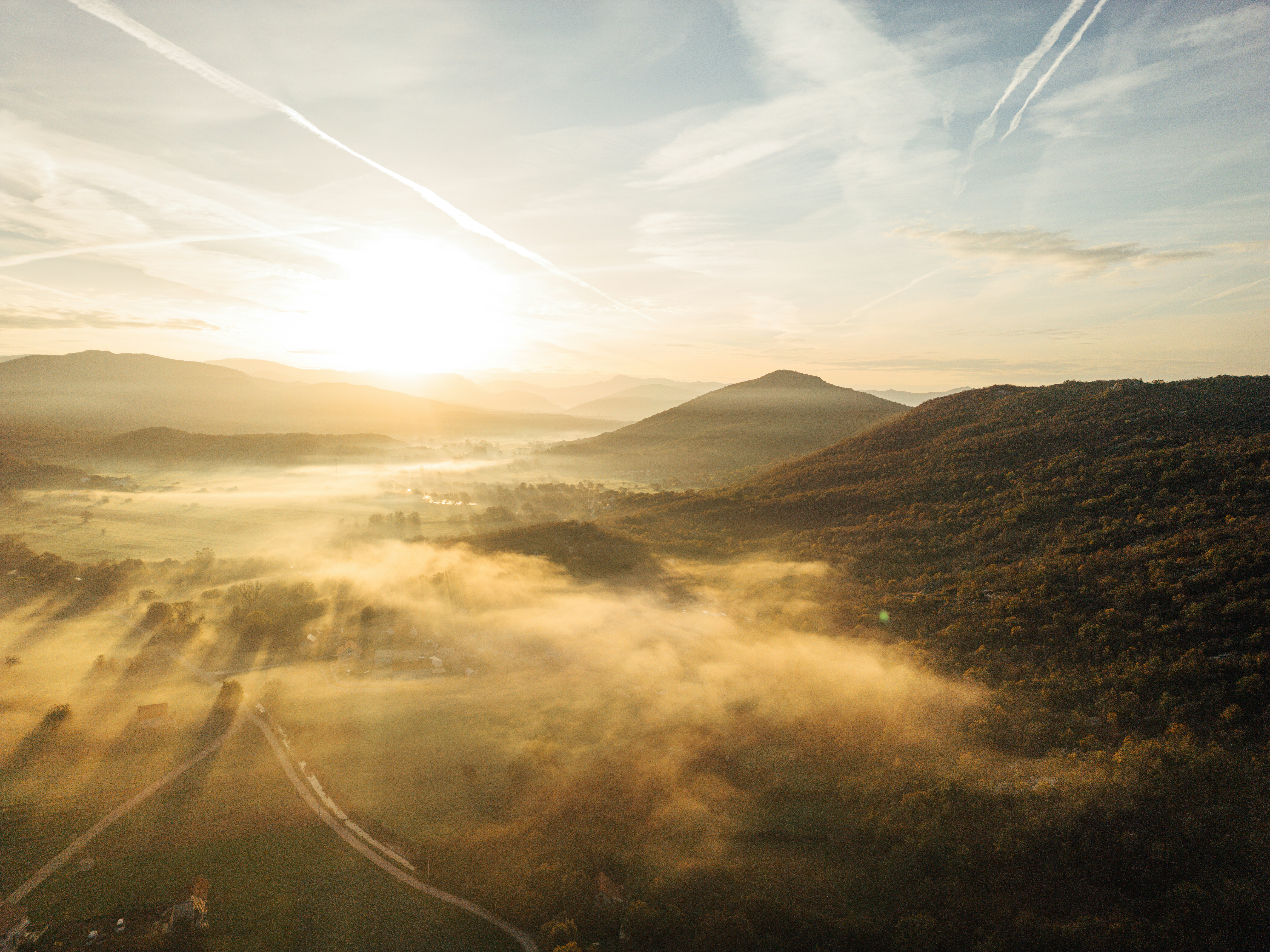 Amanecer dorado sobre montañas y bosques brumosos
