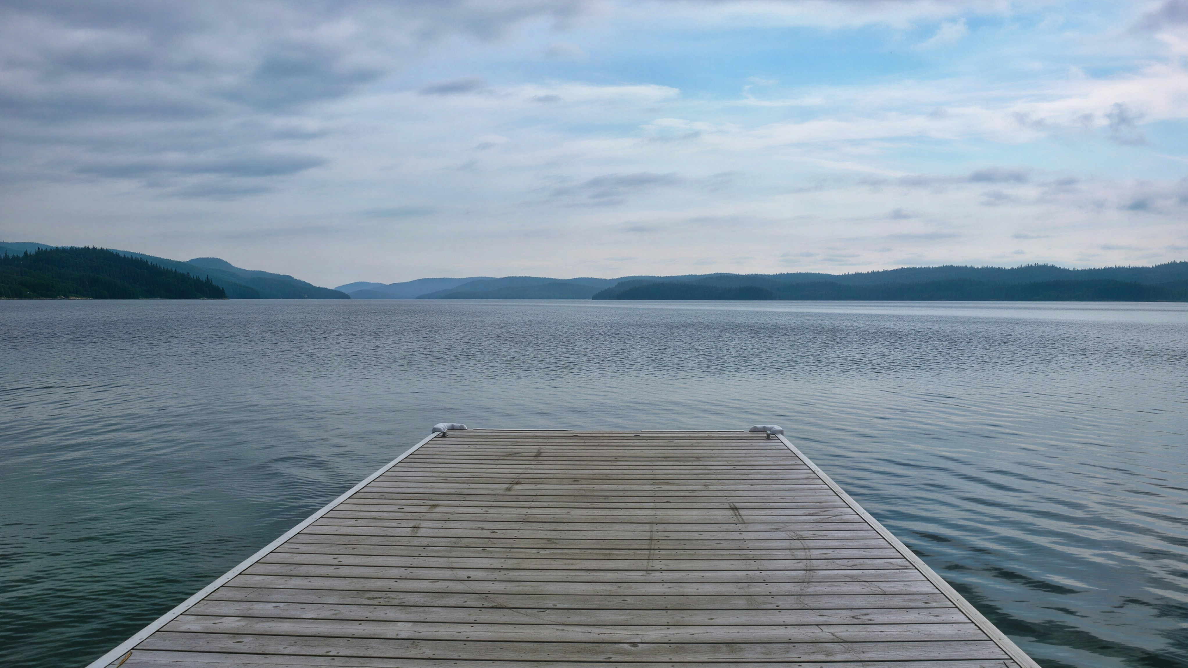 Molo di legno che si estende in un lago calmo sotto un cielo nuvoloso