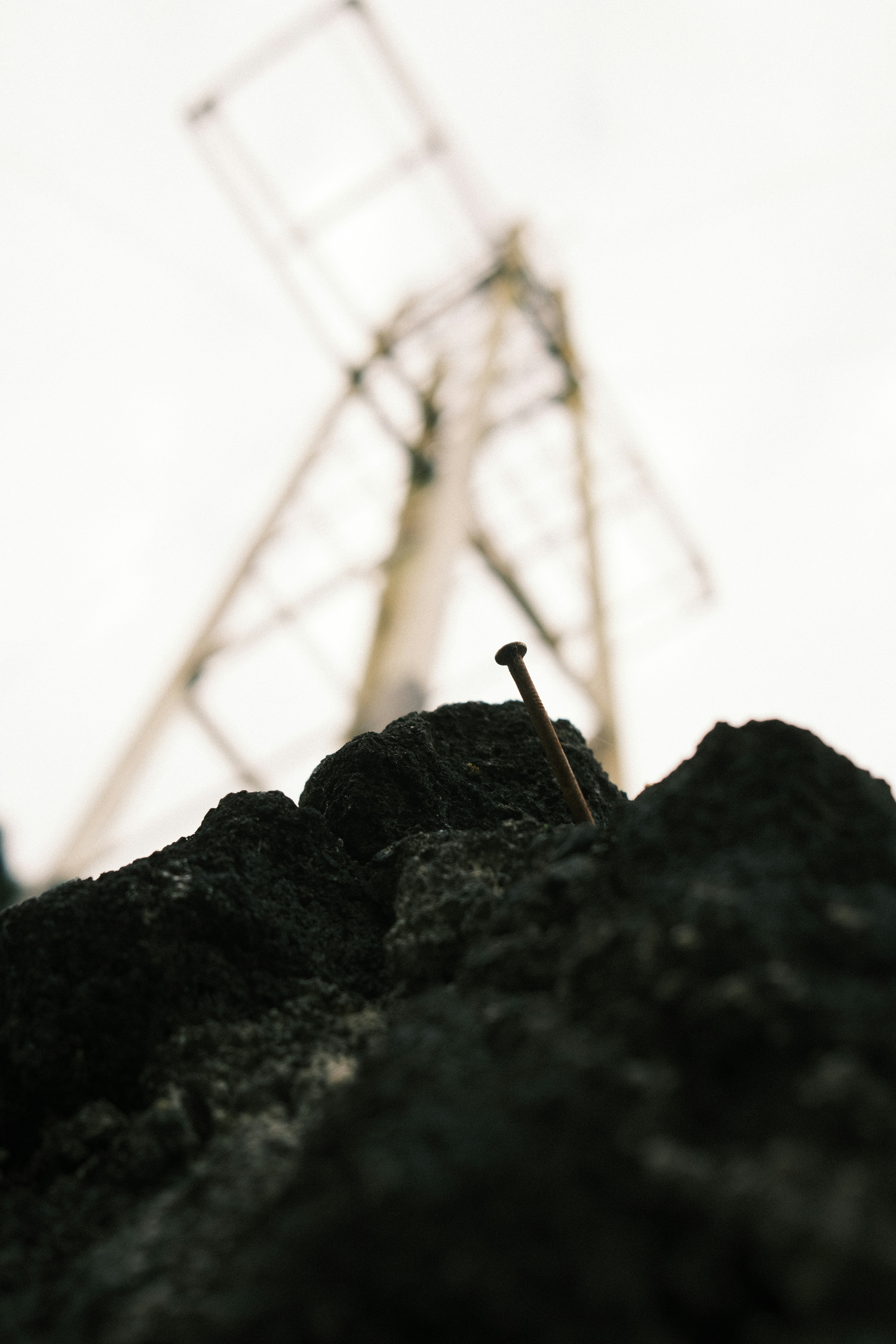 A rusty nail protrudes from dark, rough rocks.