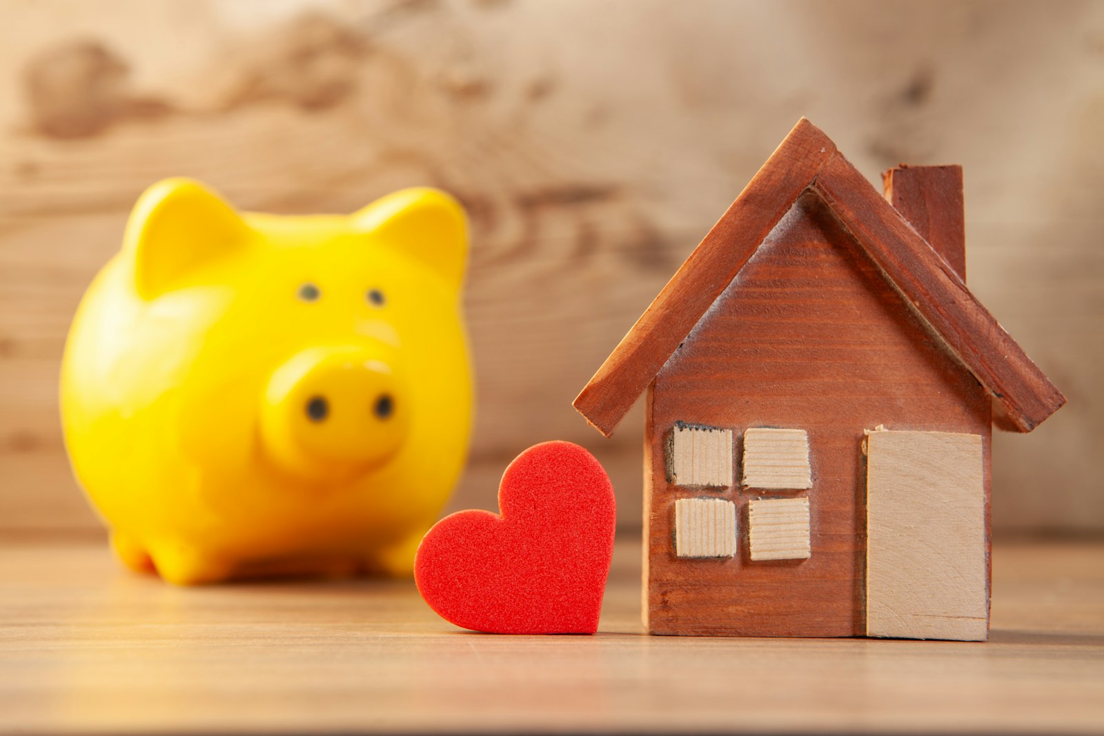 Piggy bank next to a small wooden house model representing cash to close