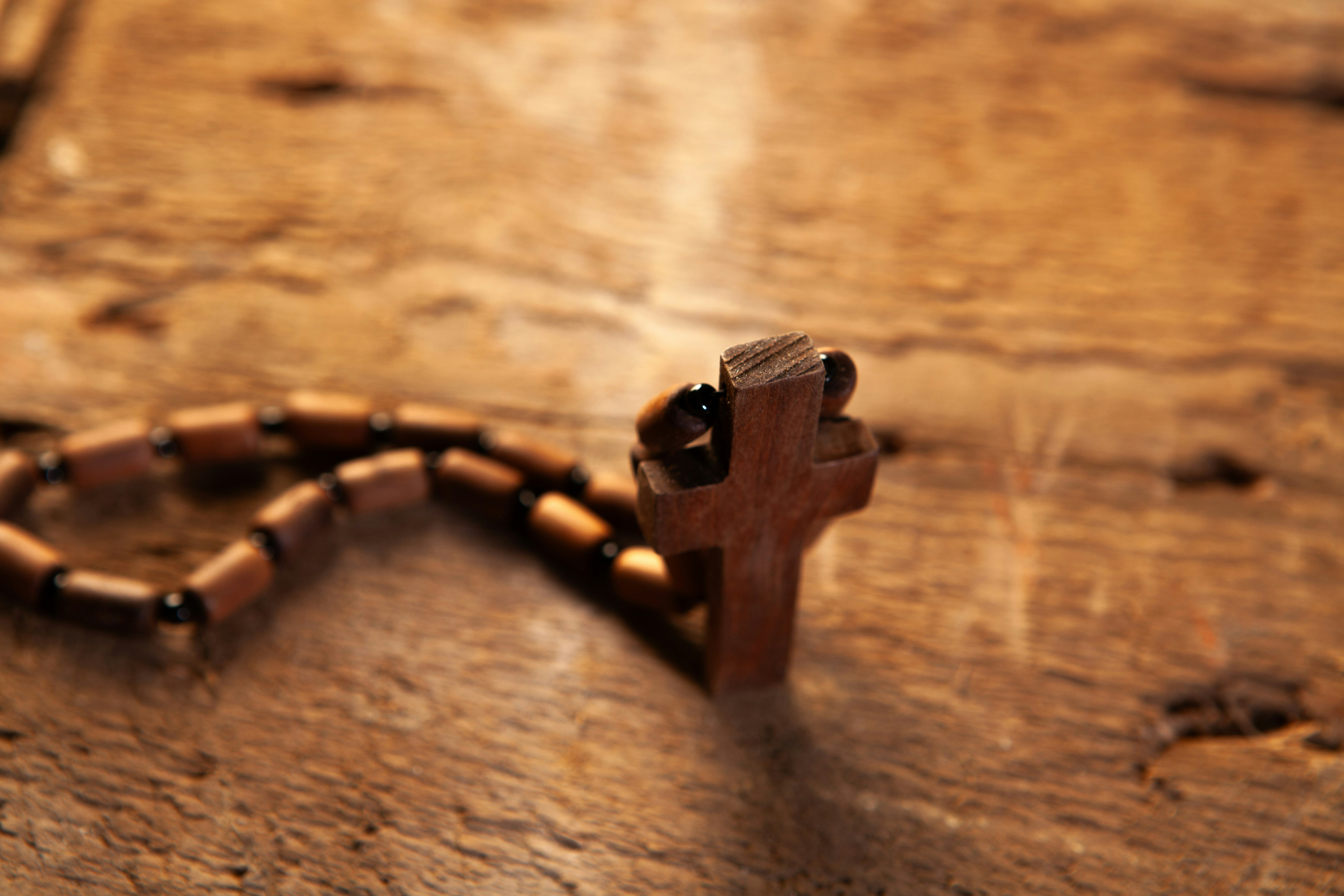 Wooden rosary beads with a cross on a wooden surface