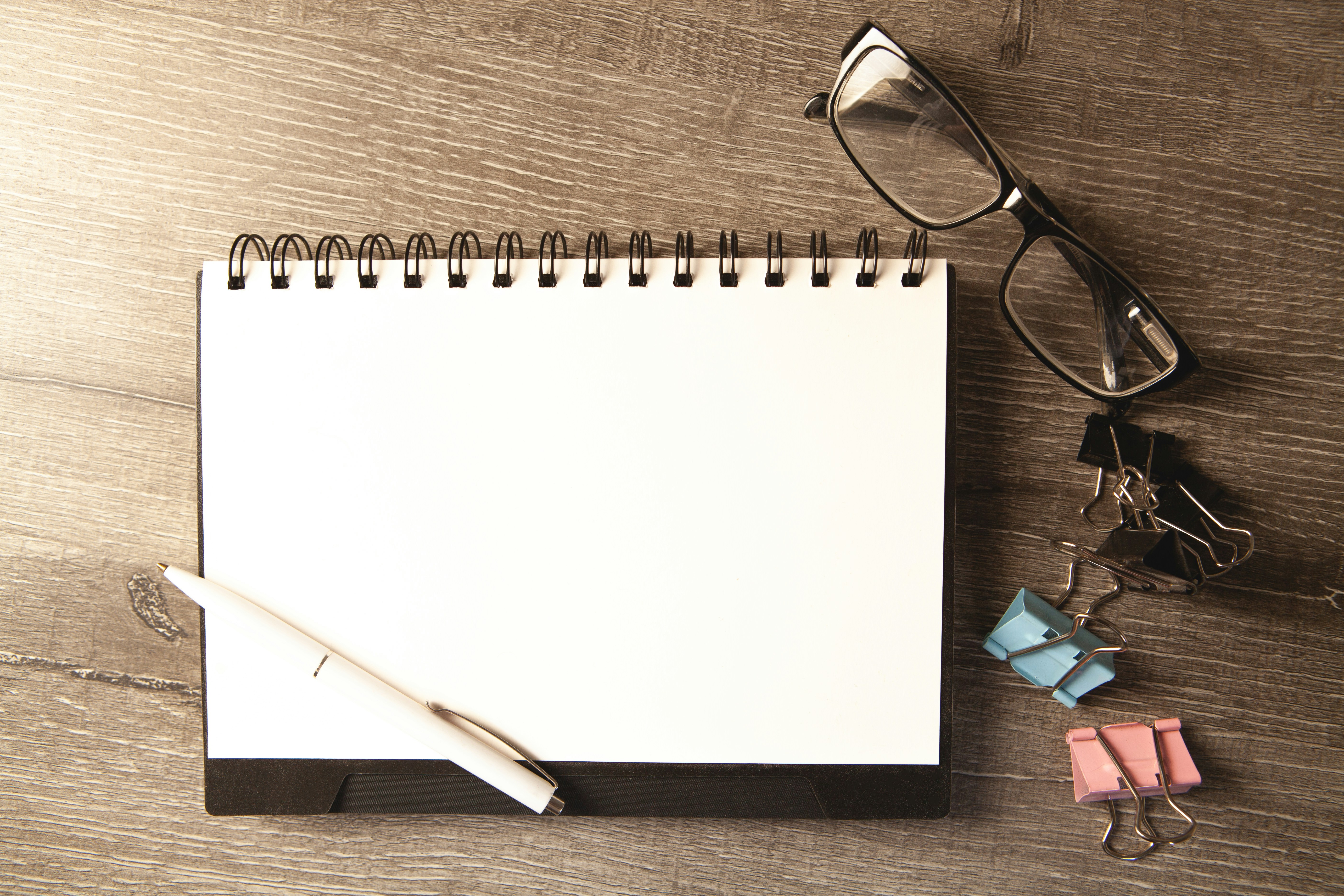 Desk with notepad, pen, glasses, and clips