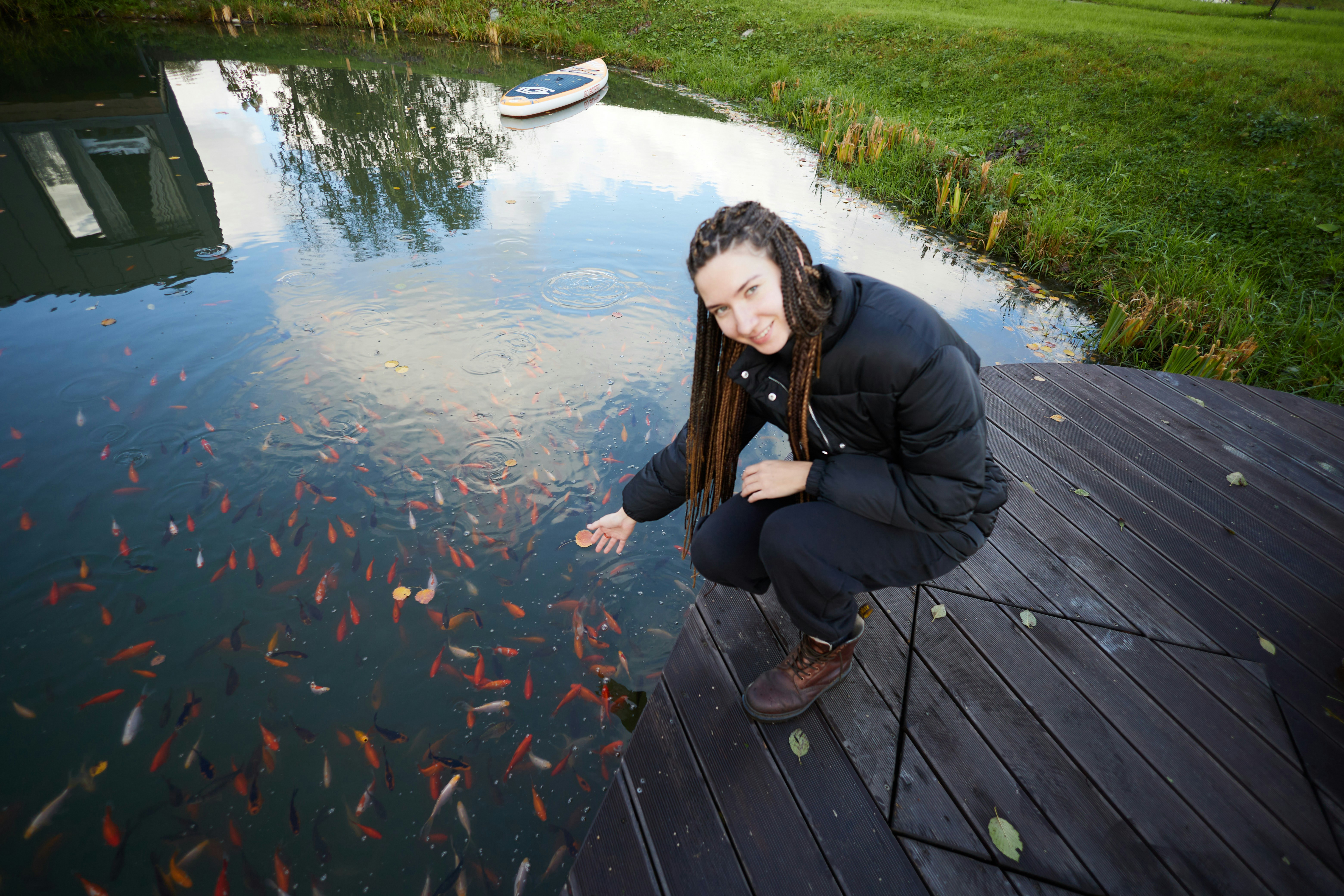 Woman feeding fish in a pond