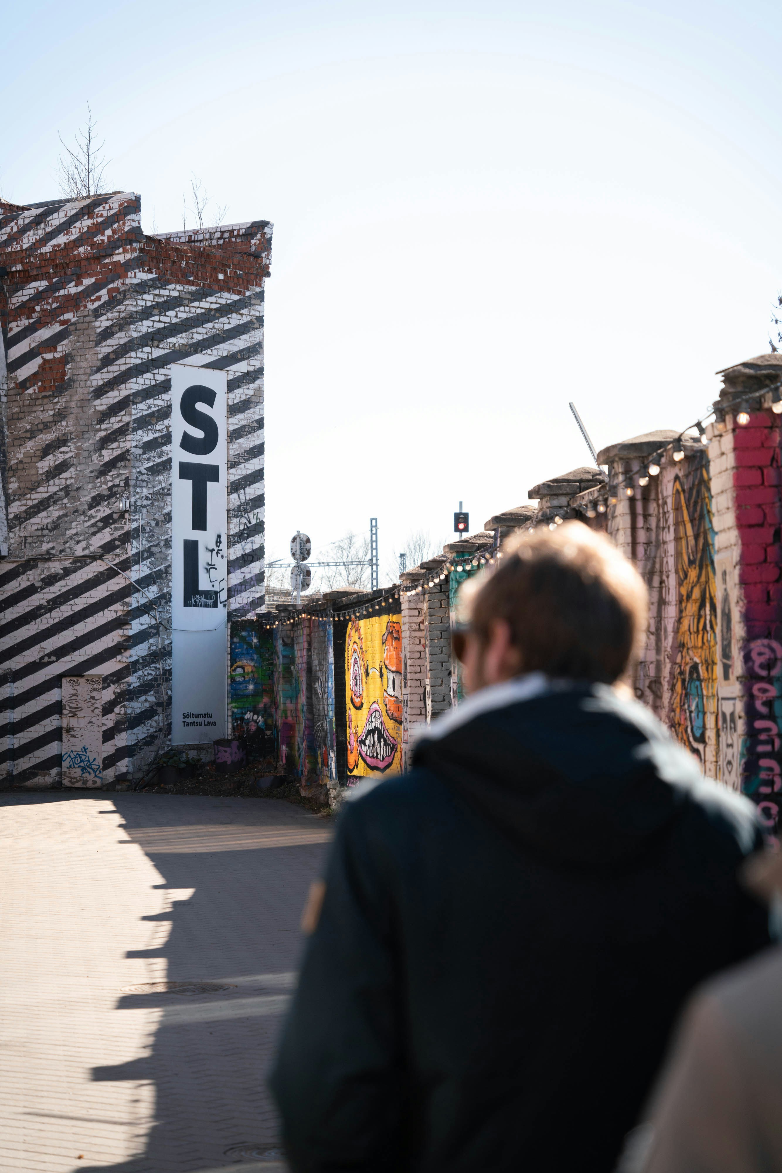 Un hombre pasa junto a graffiti en edificios de ladrillo al aire libre.