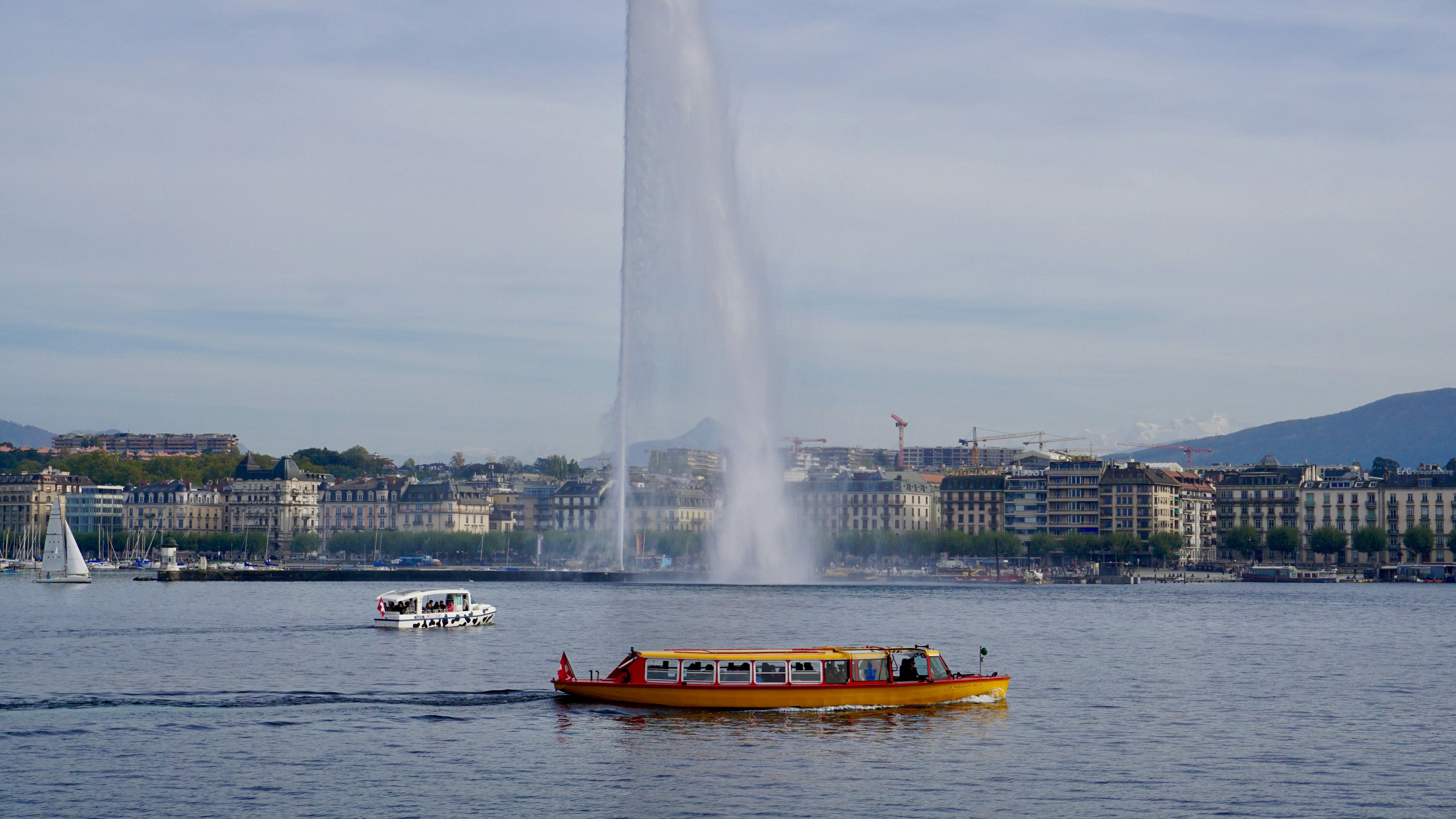 A boat on the water with a large fountain behind