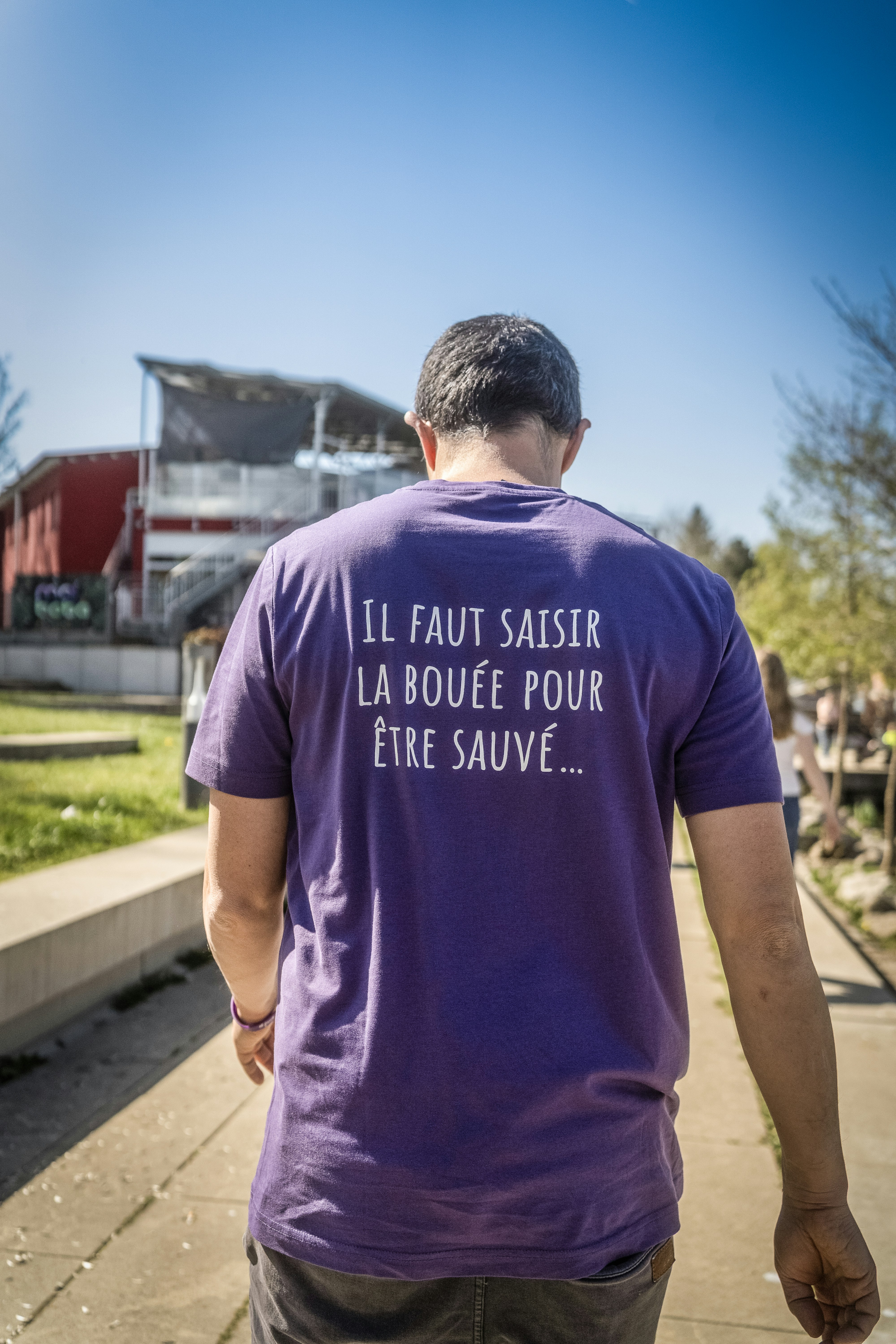 フランス語の文字が書かれた紫色のTシャツを着た男性