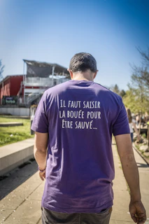 Man wearing a purple t-shirt with french text
