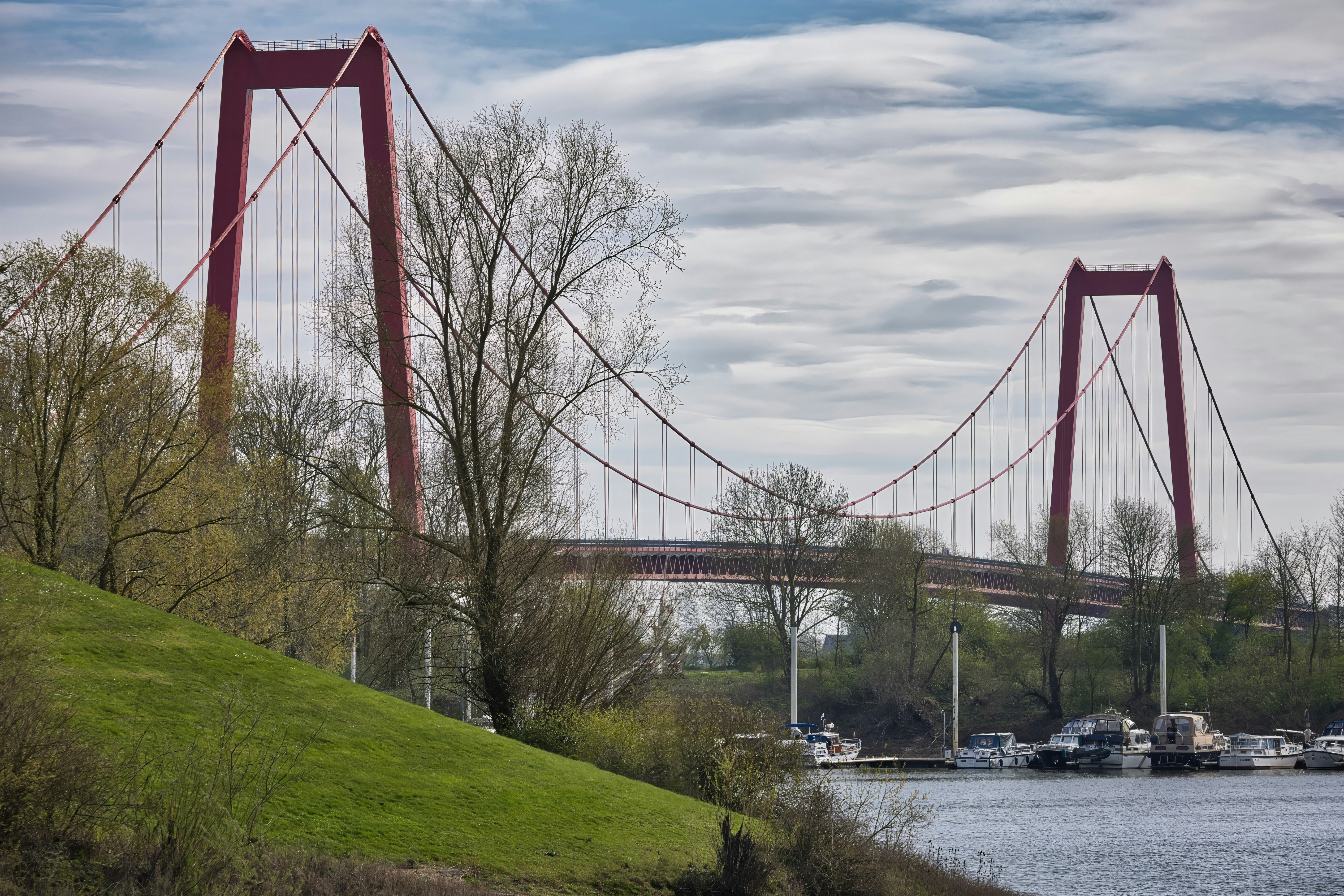 Red suspension bridge over a river with boats